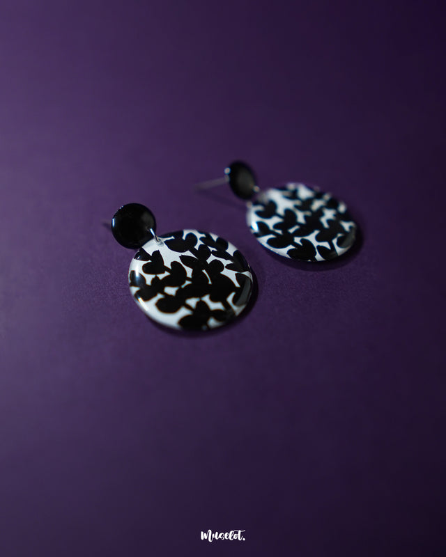 Siyahgul black floral stud earrings, showcased against a dark purple backdrop, with intricate floral patterns and a bold black finish that exude modern sophistication and timeless elegance — Muselot.