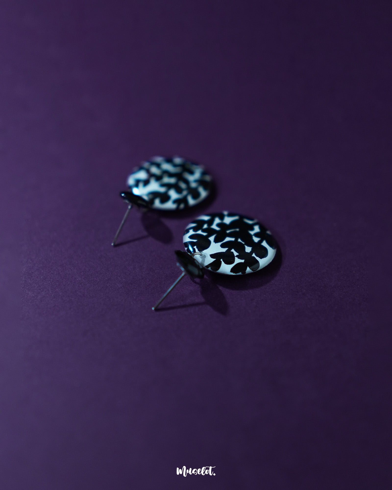 Siyahgul black floral stud earrings, highlighted against a rich purple background, with delicate floral detailing and a deep black hue that bring out their striking elegance and bold charm — Muselot.