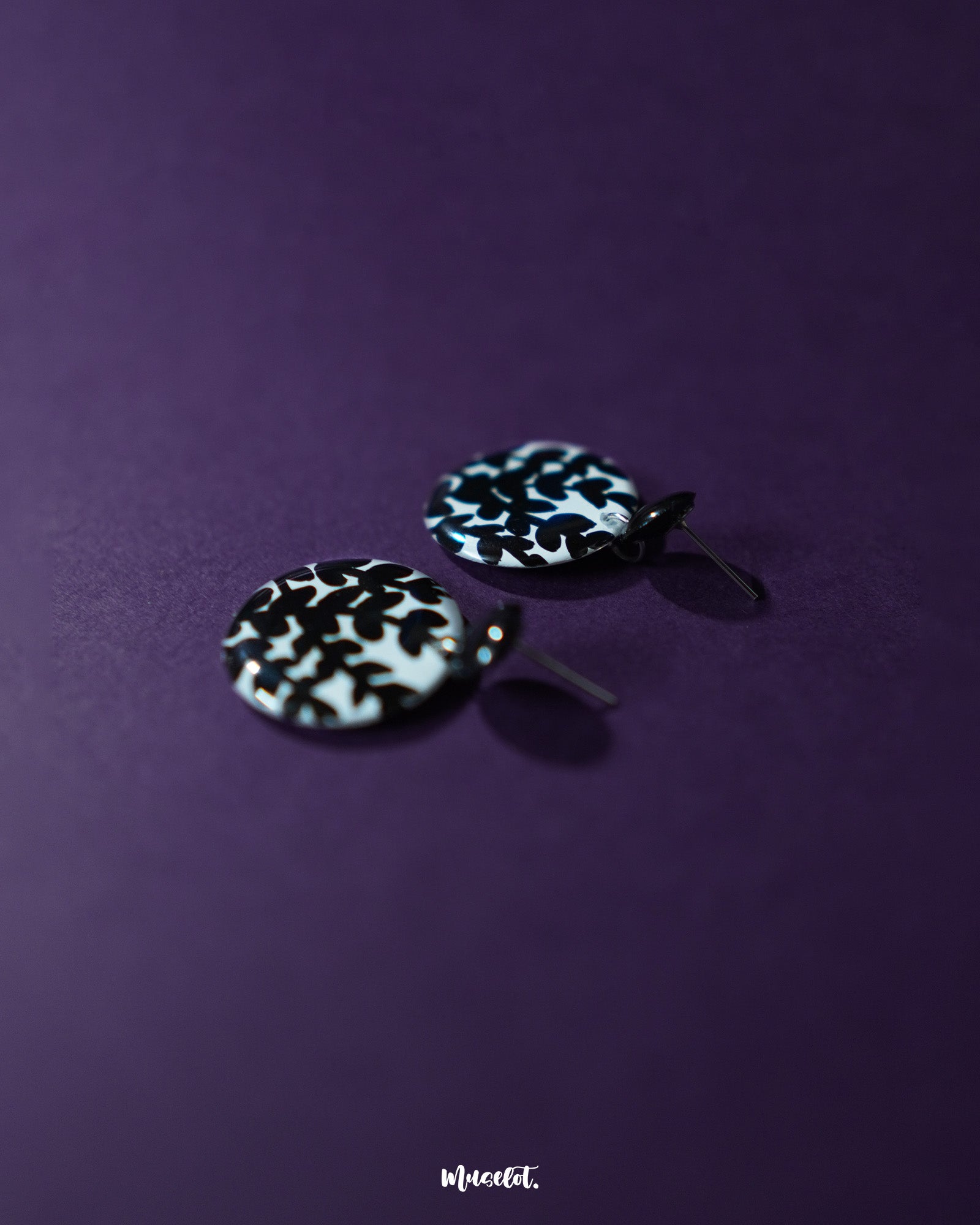 Siyahgul black floral stud earrings, set against a deep purple backdrop, featuring intricate floral elements and a bold black finish that enhance their sophisticated and contemporary appeal — Muselot.