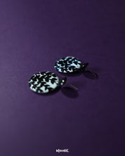 Siyahgul black floral stud earrings, set against a deep purple backdrop, featuring intricate floral elements and a bold black finish that enhance their sophisticated and contemporary appeal — Muselot.
