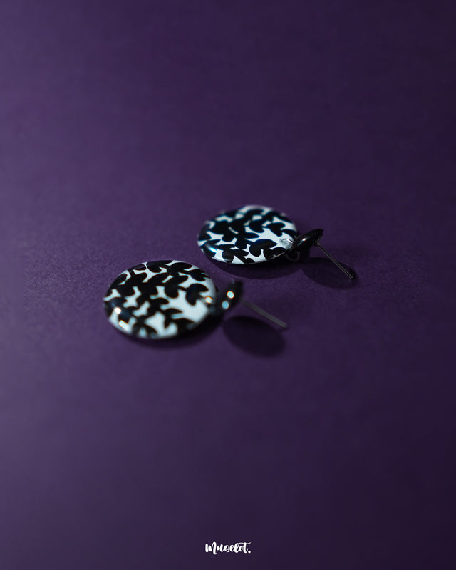 Siyahgul black floral stud earrings, set against a deep purple backdrop, featuring intricate floral elements and a bold black finish that enhance their sophisticated and contemporary appeal — Muselot.