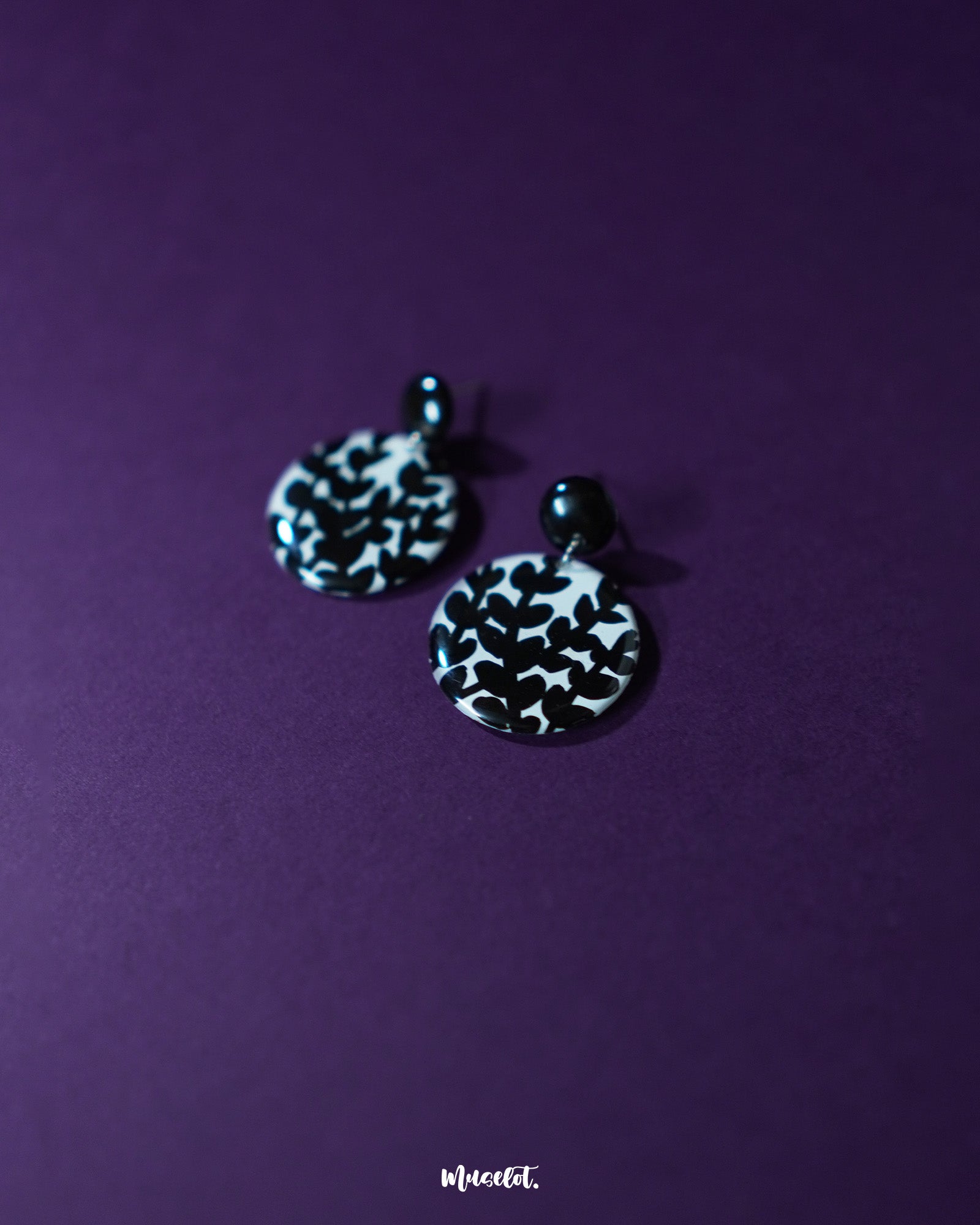 Siyahgul black floral stud earrings, beautifully framed by a dark purple background, with detailed floral accents and a striking black tone that capture both elegance and boldness — Muselot.