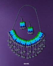 A flat lay of the Sukoon waterfall boho jewelry set displayed on a rich purple background, highlighting its cascading design of multicolored floral elements and metallic charms that evoke a free-spirited, handcrafted elegance — Muselot