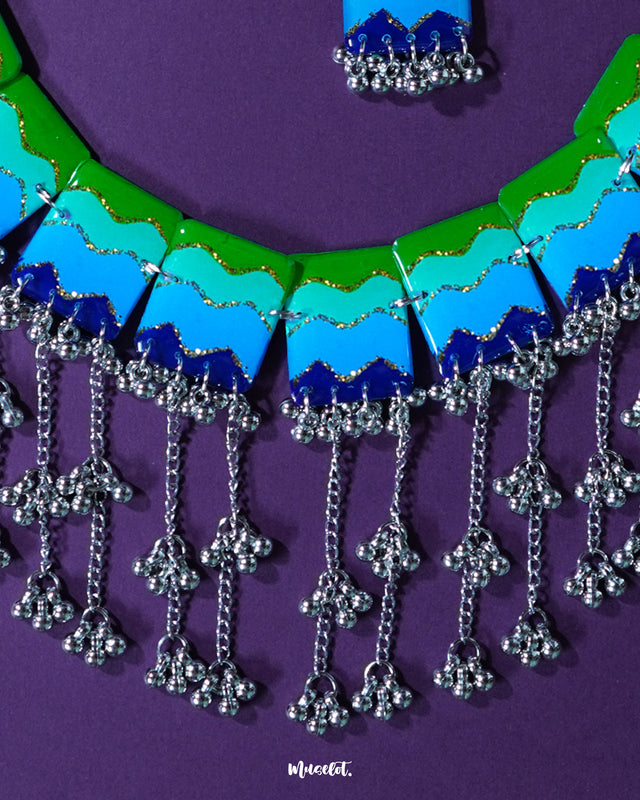 A focused view of the Sukoon waterfall boho necklace, showcasing its cascading silver-toned chains and enamel accents in soothing green and blue tones. The design highlights its earthy elegance and statement-making boho appeal — Muselot.