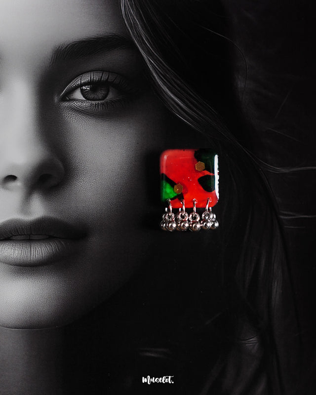 A model wears the Surkhbaagh handmade earrings, featuring bold red and green abstract blocks adorned with reflective sequins and finished with delicate silver-toned beadwork. The earrings beautifully highlight traditional craftsmanship with a contemporary twist, adding a vibrant statement to the overall look — Muselot.