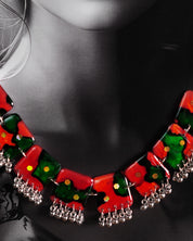 A model showcases the complete Surkhbaagh handmade jewelry set, including the vivid red-and-green block necklace and matching earrings, both accented with mirror sequins and delicate silver-toned beads. The set stands out against the outfit, highlighting its artistic flair and making it perfect for festive and cultural occasions — Muselot.
