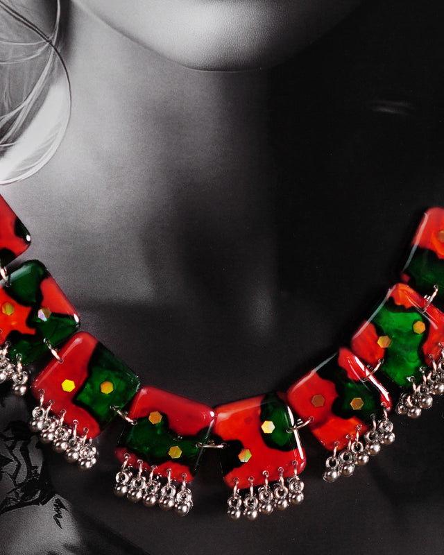 A model showcases the complete Surkhbaagh handmade jewelry set, including the vivid red-and-green block necklace and matching earrings, both accented with mirror sequins and delicate silver-toned beads. The set stands out against the outfit, highlighting its artistic flair and making it perfect for festive and cultural occasions — Muselot.