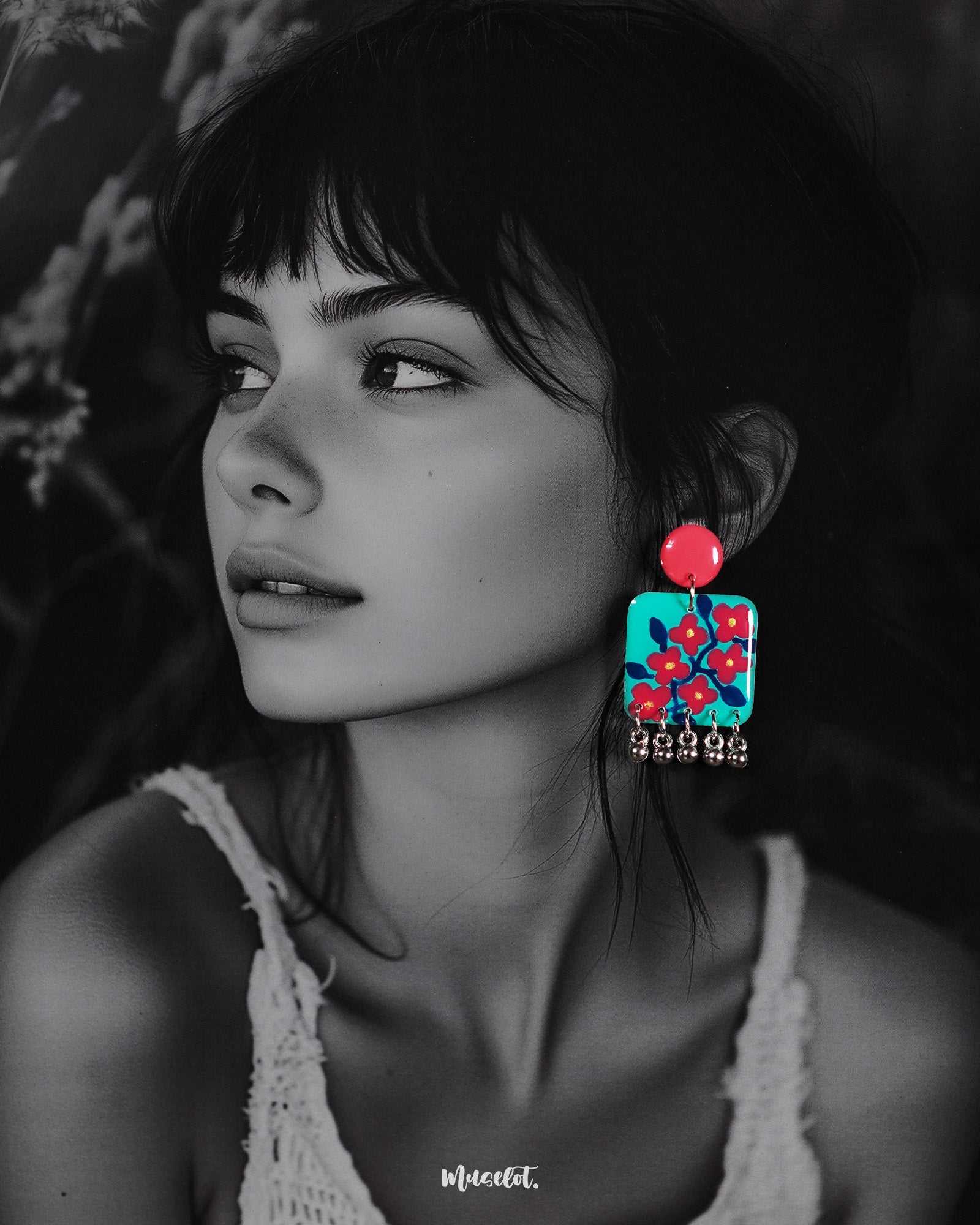 A woman models the Surkhili floral earrings, showcasing their bold turquoise and red design with hand-painted floral details and silver ghungroo accents, adding a vibrant pop of color to her look — Muselot.