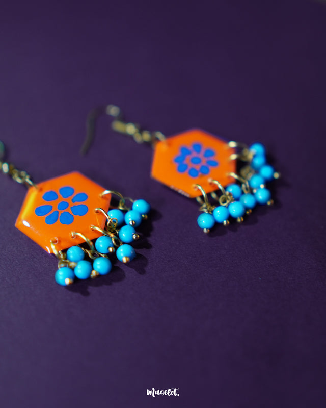 Surkhshaam orange floral stud drop earrings, set against a soft backdrop, with vivid blue petals and a delicate drop design that exude a lively and sophisticated boho charm — Muselot.