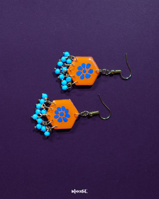 Surkhshaam orange floral stud drop earrings, framed by a rich purple background, with striking blue floral details and a delicate drop that highlight their playful yet sophisticated boho charm — Muselot.