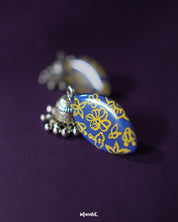 Elegant Tabeer blue jhumkas, adorned with fine floral detailing, stand out beautifully against a soft purple background, showcasing their traditional charm with a modern touch — Muselot.
