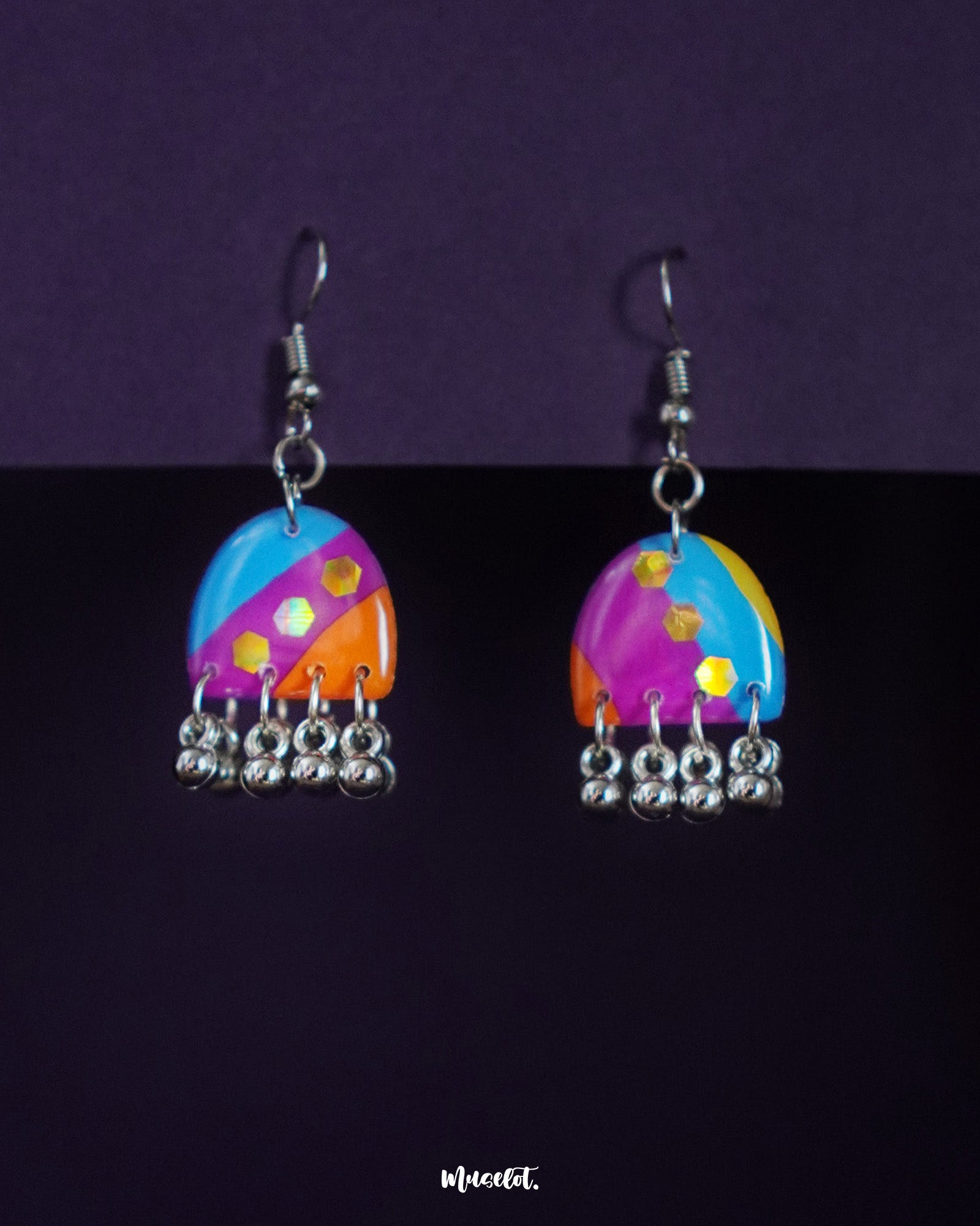 Ufaq multicolor hook earrings elegantly drape against a deep, neutral background, with vibrant hues and patterns that exude a playful yet refined charm — Muselot.