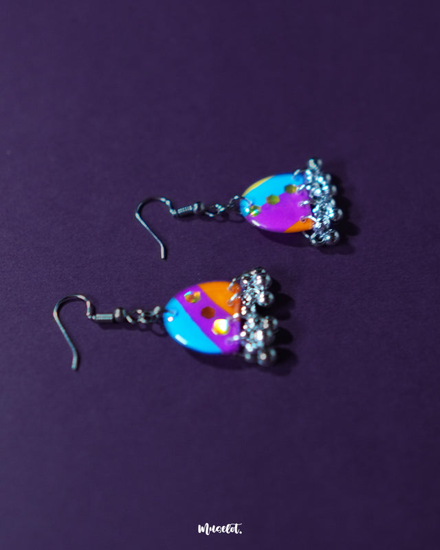 Ufaq multicolor hook earrings, framed against a deep purple background, showcasing vibrant hues and intricate patterns that highlight the earrings' striking and sophisticated design — Muselot.