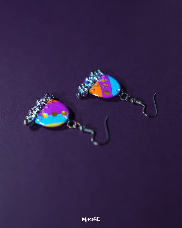 Ufaq multicolor hook earrings, beautifully contrasted against a deep purple backdrop, with a vibrant mix of hues and bold patterns that showcase their playful yet chic design — Muselot.
