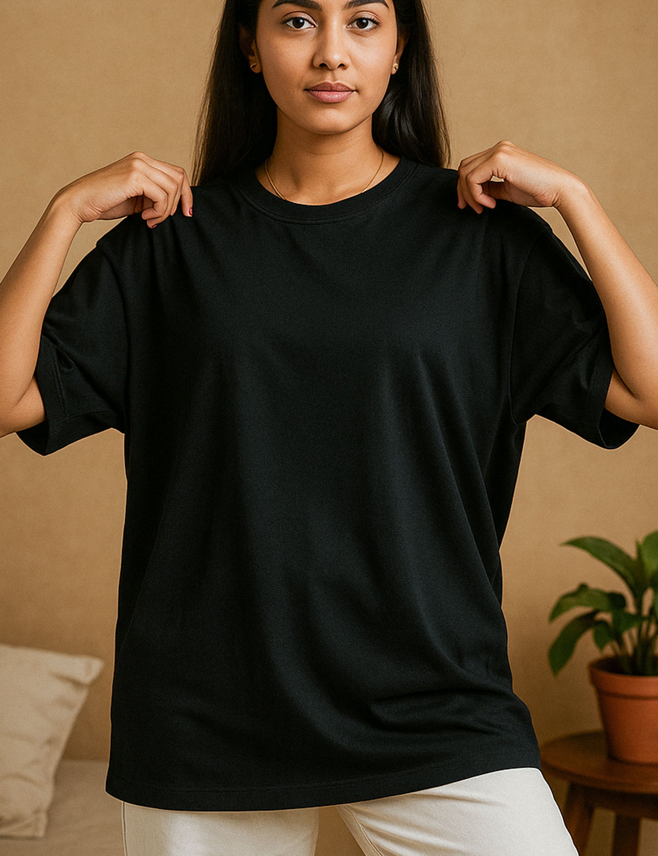 A model wearing a unisex oversized black T-shirt gently adjusting the collar, showcasing the minimal lifestyle appeal and effortless charm of this versatile wardrobe essential tee for an everyday wear — Muselot.