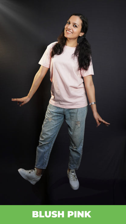 A stylish model happily poses in a plain, casual blush pink t-shirt with cheerful expression and fun pose complementing the simple, versatile top, highlighting a cool easy fit-muselot