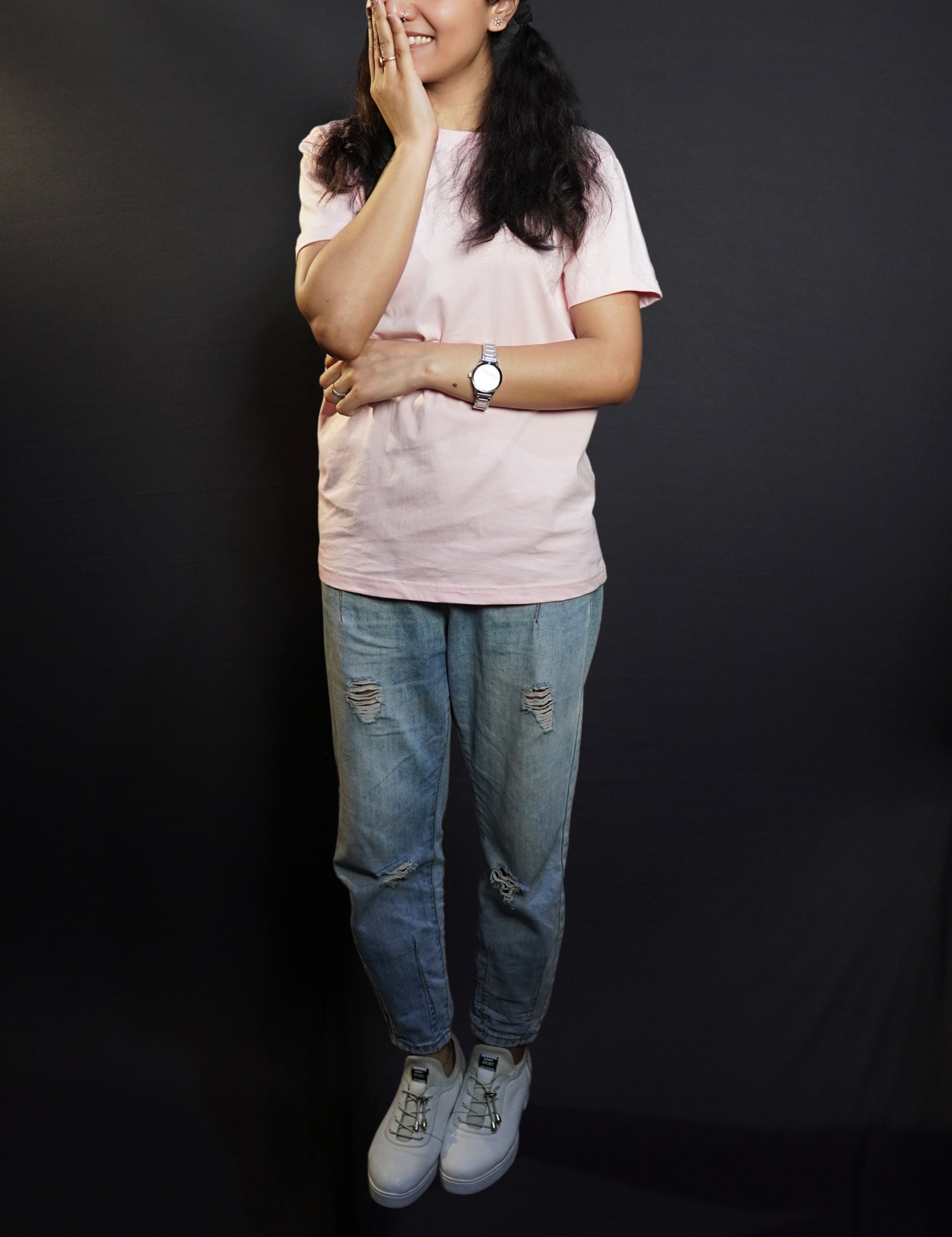 A young model wearing a blush pink unisex t shirt with a simple, short-sleeved design, pairing the top with ripped blue jeans, highlighting a casual, everyday look-muselot