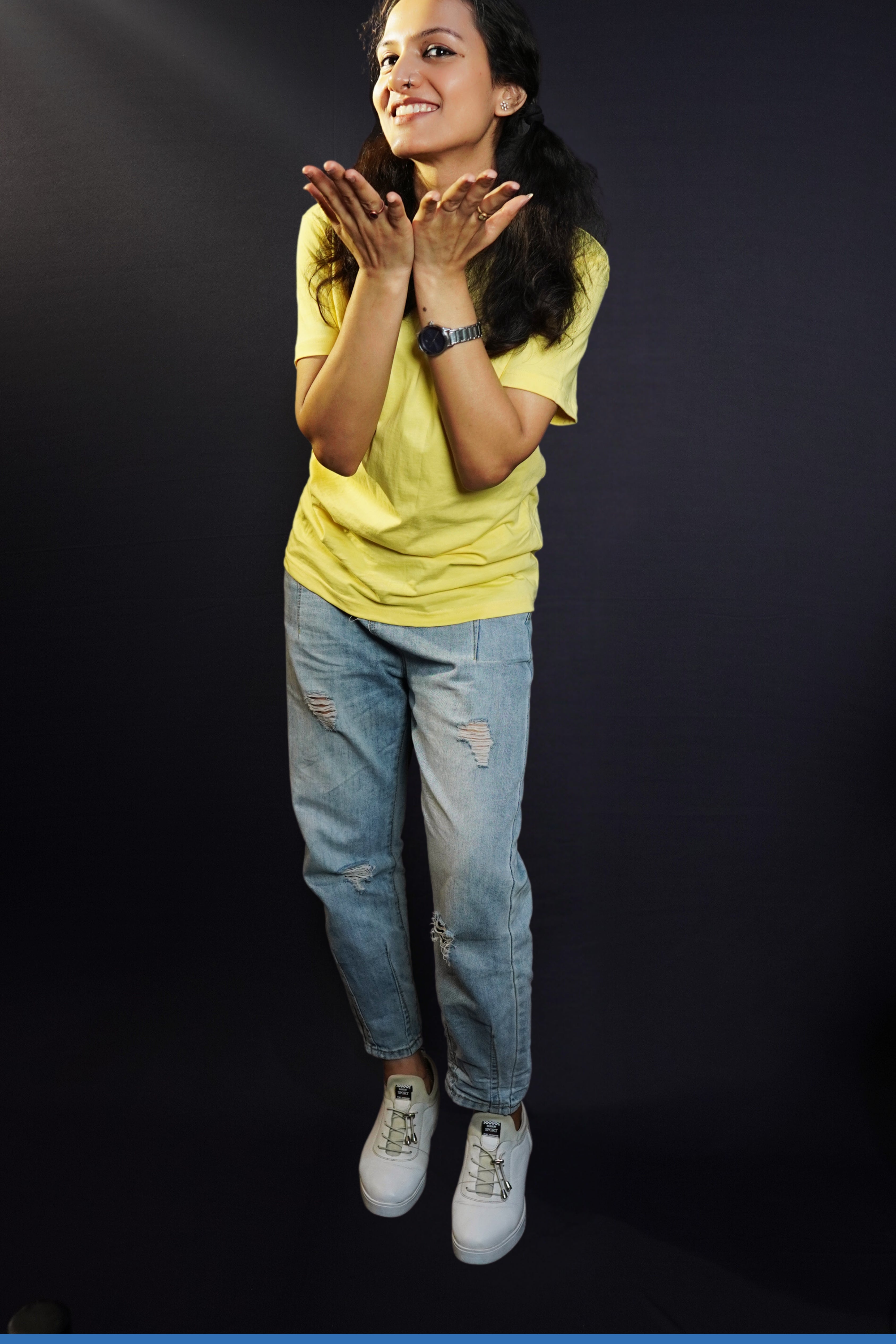 A woman posing happily with her hands directing forward, wearing a long length round neck plain adult's t-shirt, highlighting an elegant drapye look-Muselot