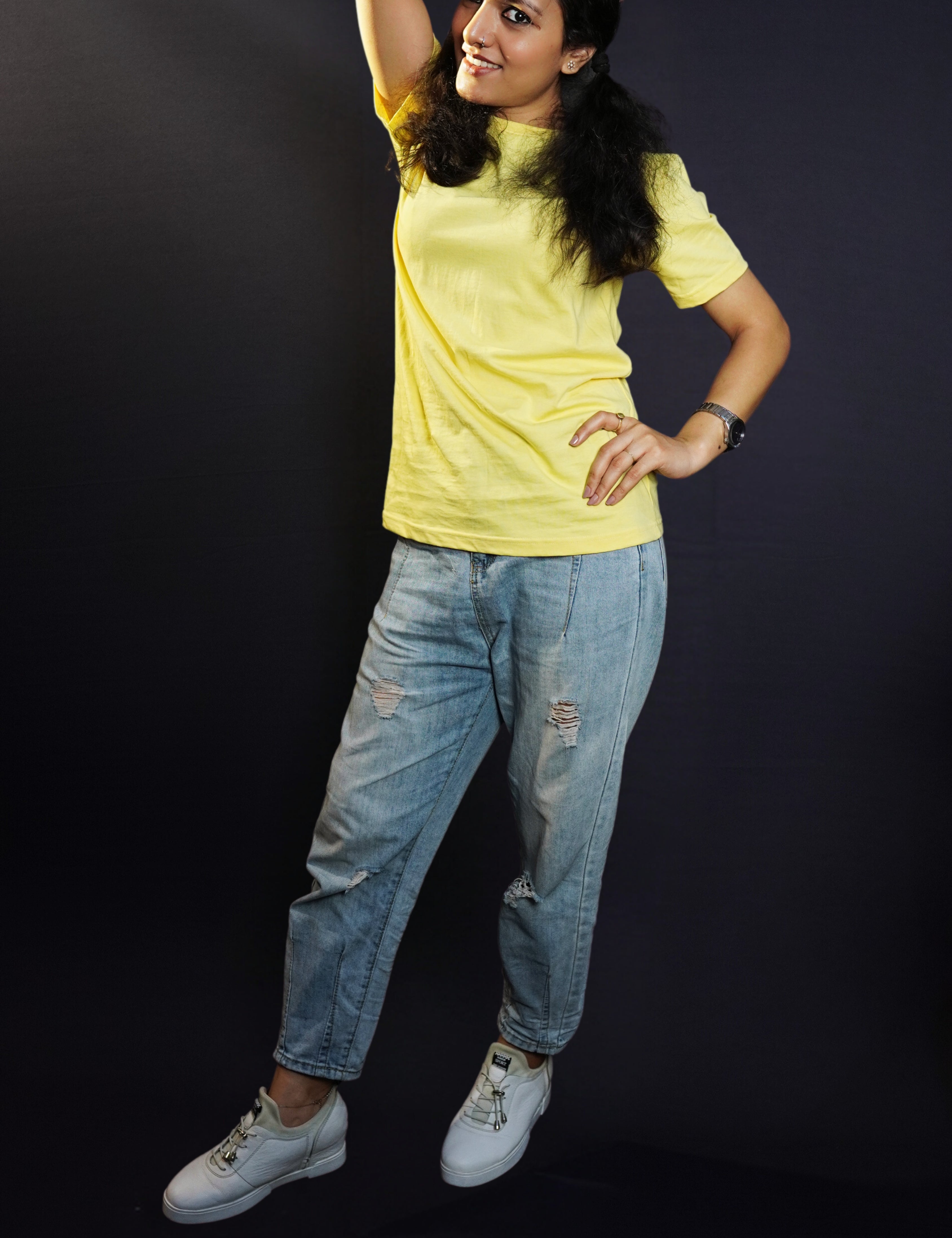 A woman wearing a plain cotton summer butter yellow t-shirt, posing with her hand on her waist and another behind the back of her head, showcasing a trendy voguish look-Muselot