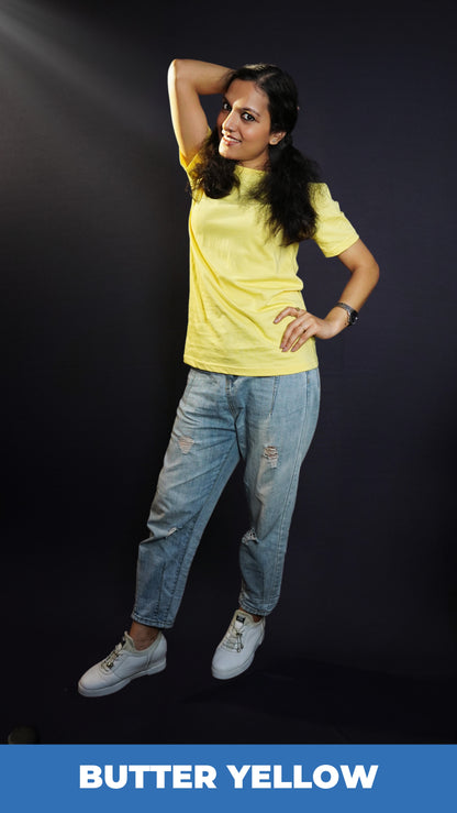 A woman wearing a plain cotton summer butter yellow t-shirt, posing with her hand on her waist and another behind the back of her head, showcasing a trendy voguish look-Muselot