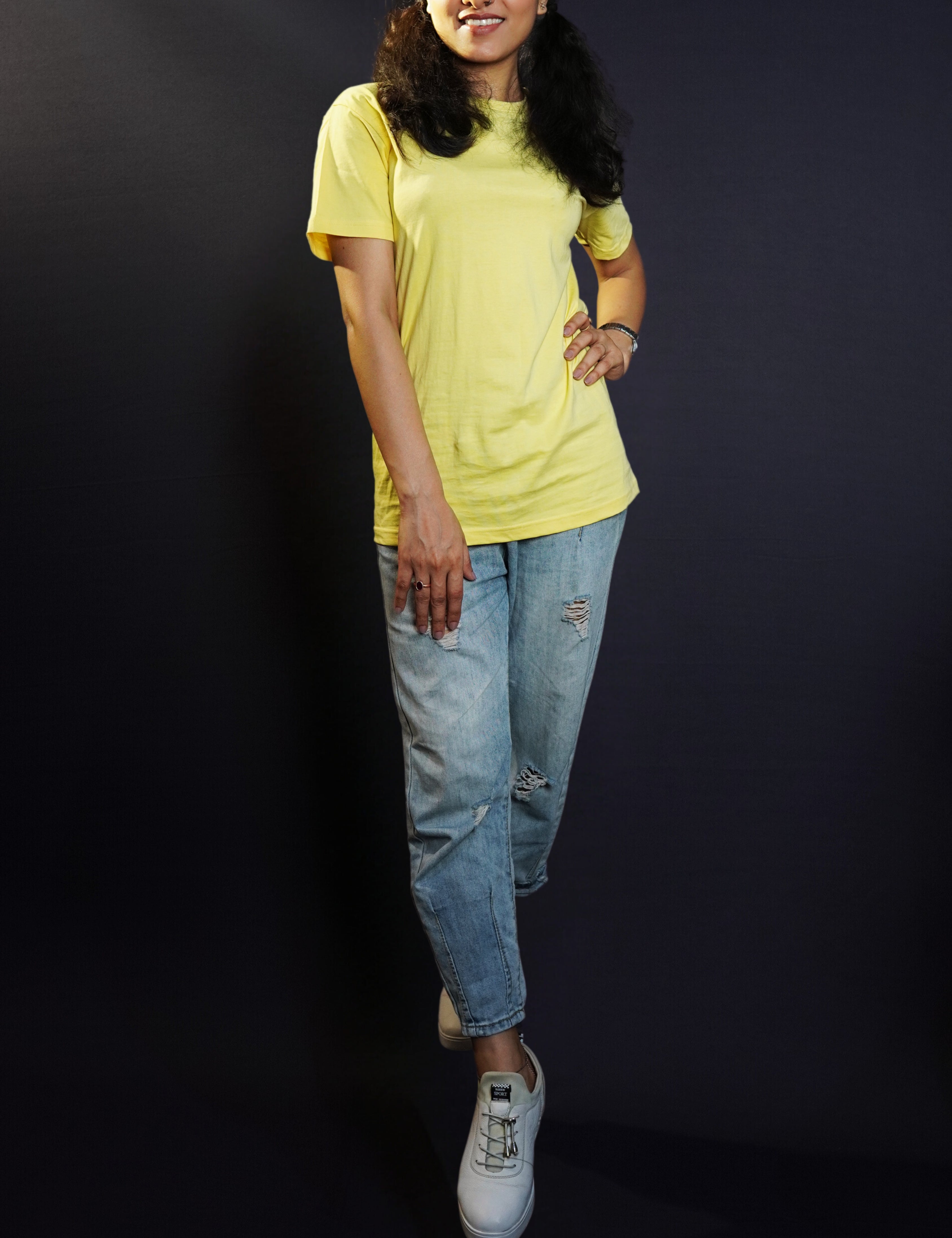 A model posing confidently as her hand relaxes on her thigh and another placed on her waist as she stands slightly sideway in a cool butter yellow round neck plain t-shirt, showcasing a cool comfortable look-Muselot