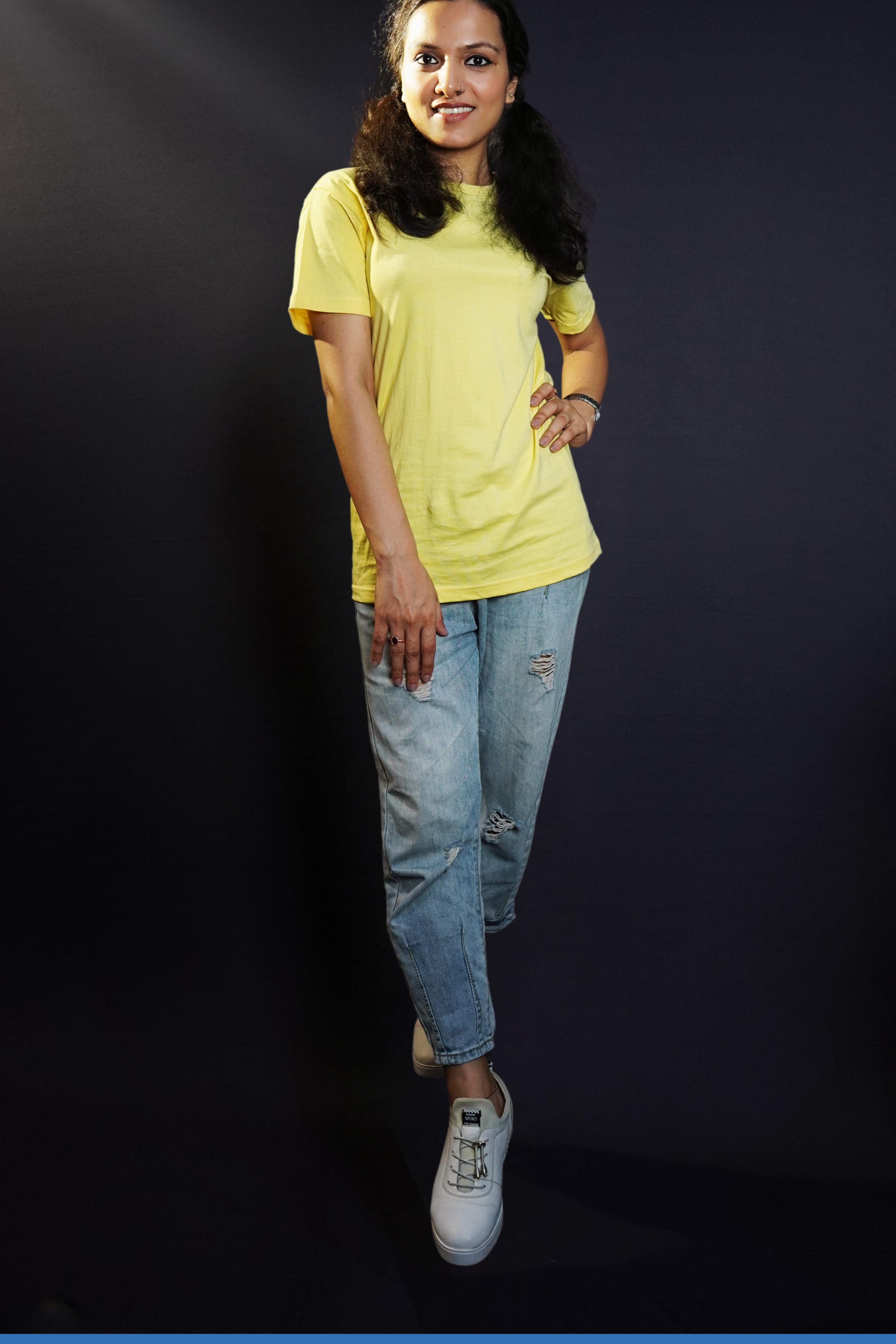 A model posing confidently as her hand relaxes on her thigh and another placed on her waist as she stands slightly sideway in a cool butter yellow round neck plain t-shirt, showcasing a cool comfortable look-Muselot