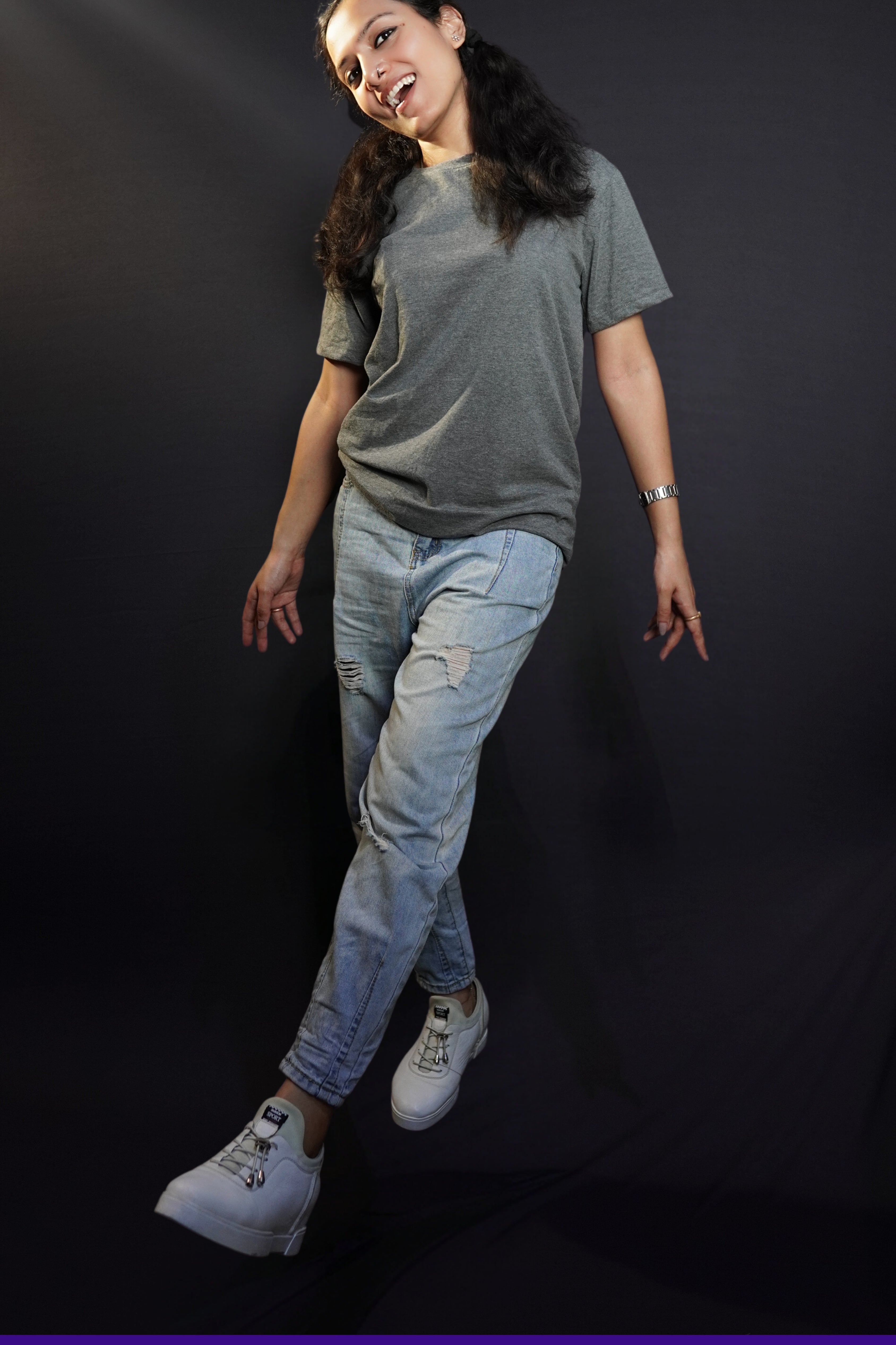 a woman wearing charcoal grey plain t shirt and ripped jeans walking and singing happily-muselot