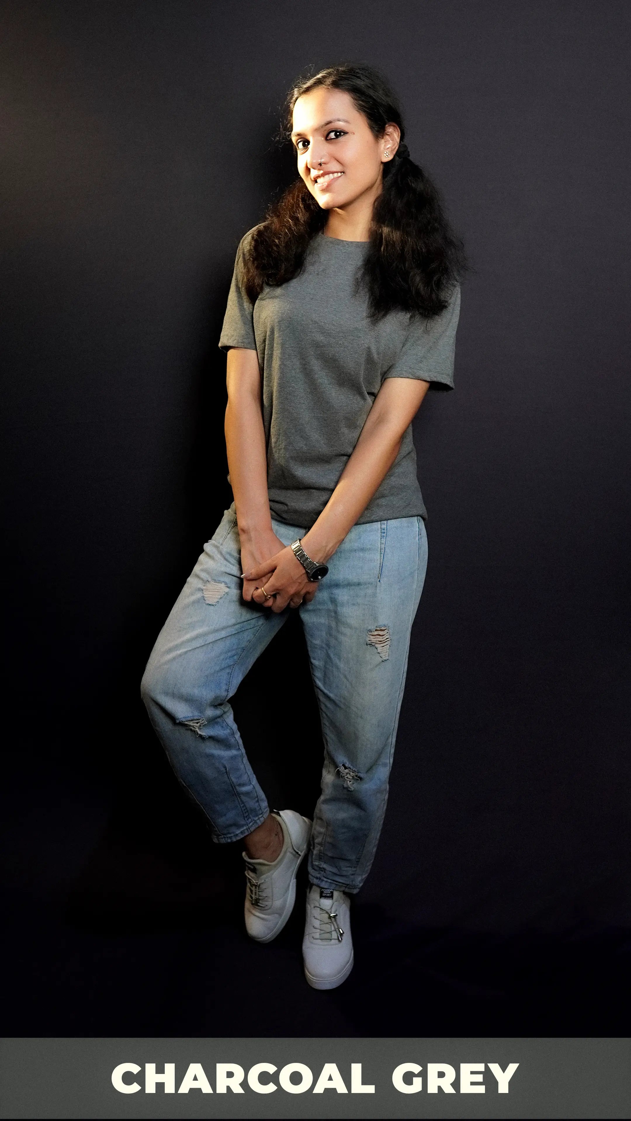 A stylish model with a smile on her face wearing long length t shirt pairing with ripped jeans and white shoes and a silver watch around her wrist, highlighting the comfy and casual outfit-Muselot