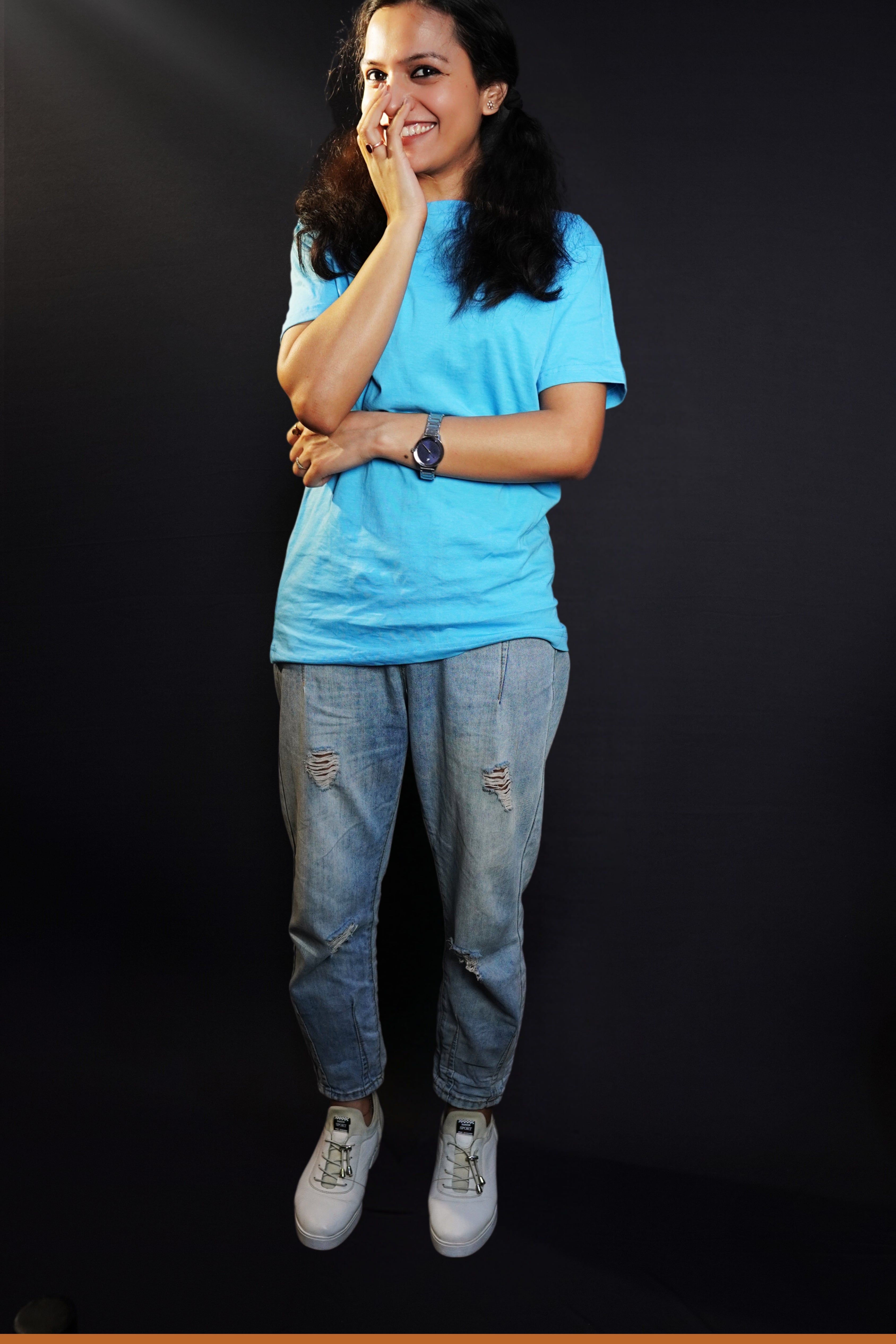 A woman laughing with her hand on the side of her mouth, wearing a cool summer short sleeved stretchable unisex cloudless blue t-shirt, showcasing a relaxed snug fit-Muselot