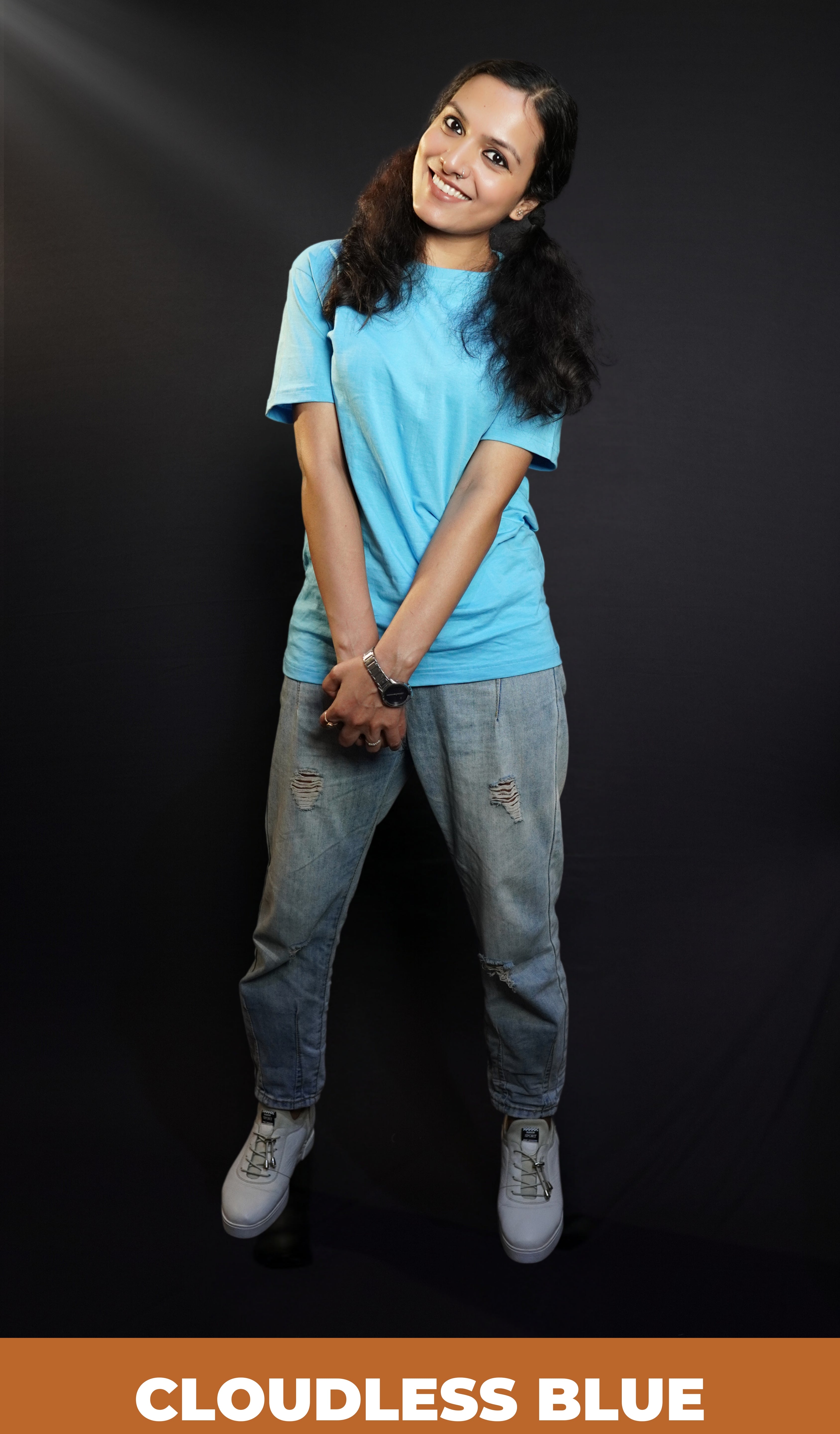 A happy woman wearing a unisex stretchable t shirt, looking at the camera with her head bent sideways, holding her hands together, highlighting a relaxed casual fit-Muselot