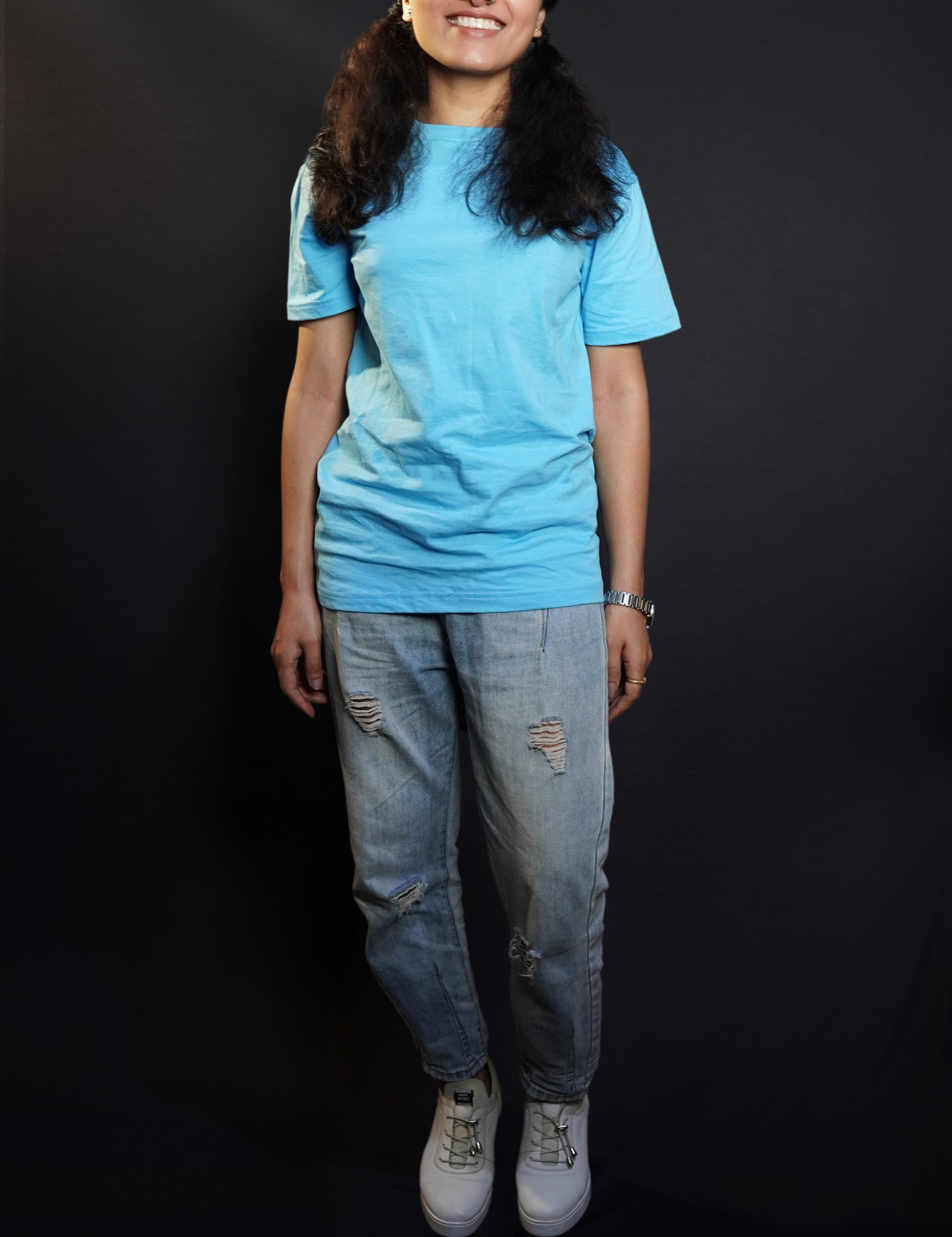 A woman smiling brightly in a plain cotton long length clouldless blue t-shirt, standing in a relaxed way, showcasing a casual popular style-Muselot