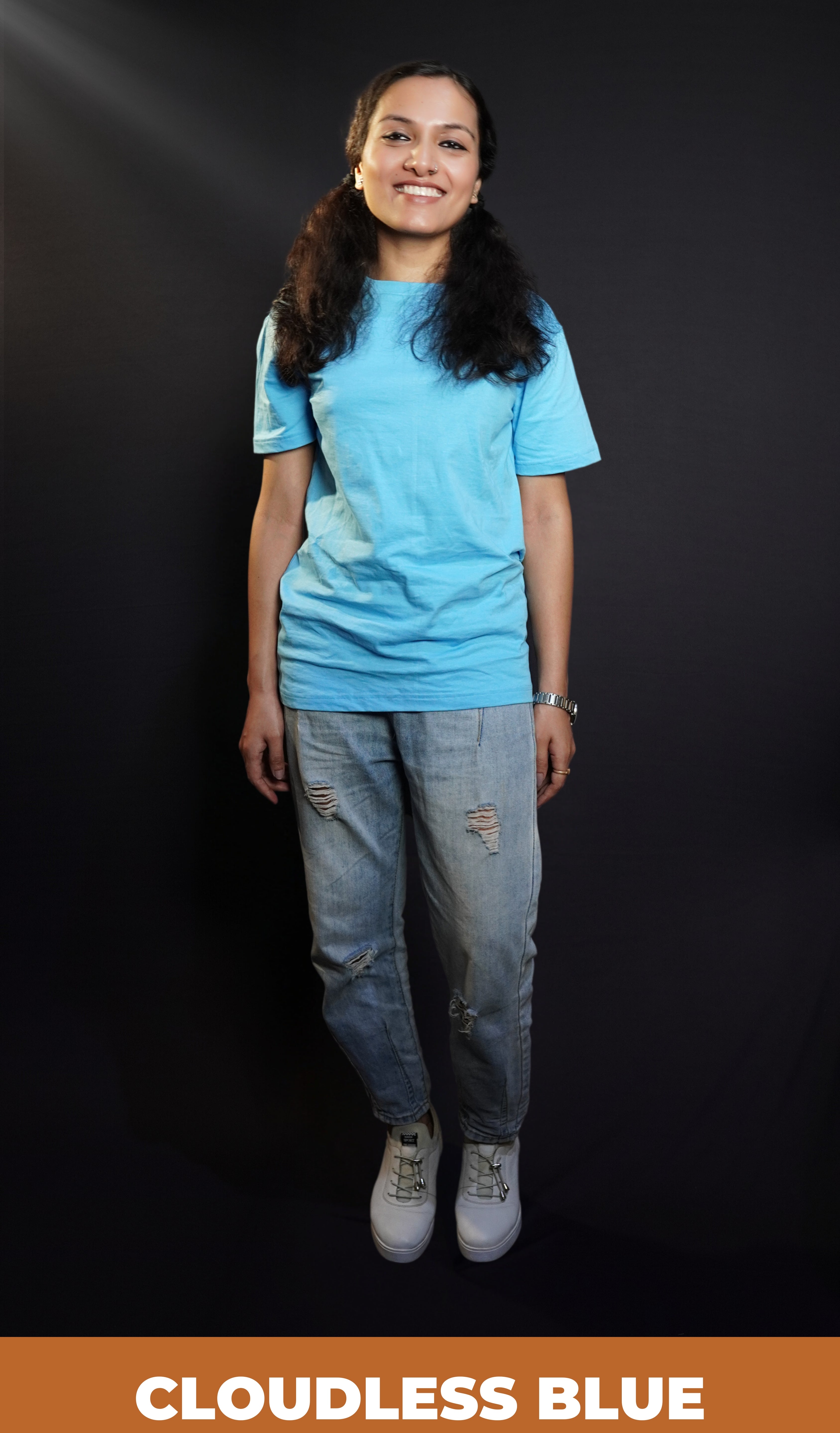 A woman smiling brightly in a plain cotton long length clouldless blue t-shirt, standing in a relaxed way, showcasing a casual popular style-Muselot