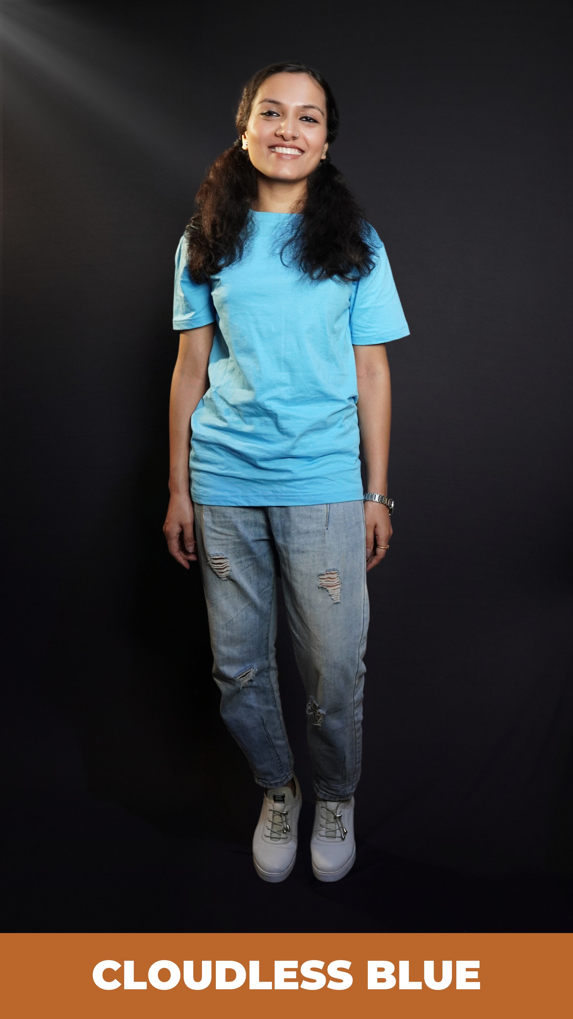 A woman smiling brightly in a plain cotton long length clouldless blue t-shirt, standing in a relaxed way, showcasing a casual popular style-Muselot