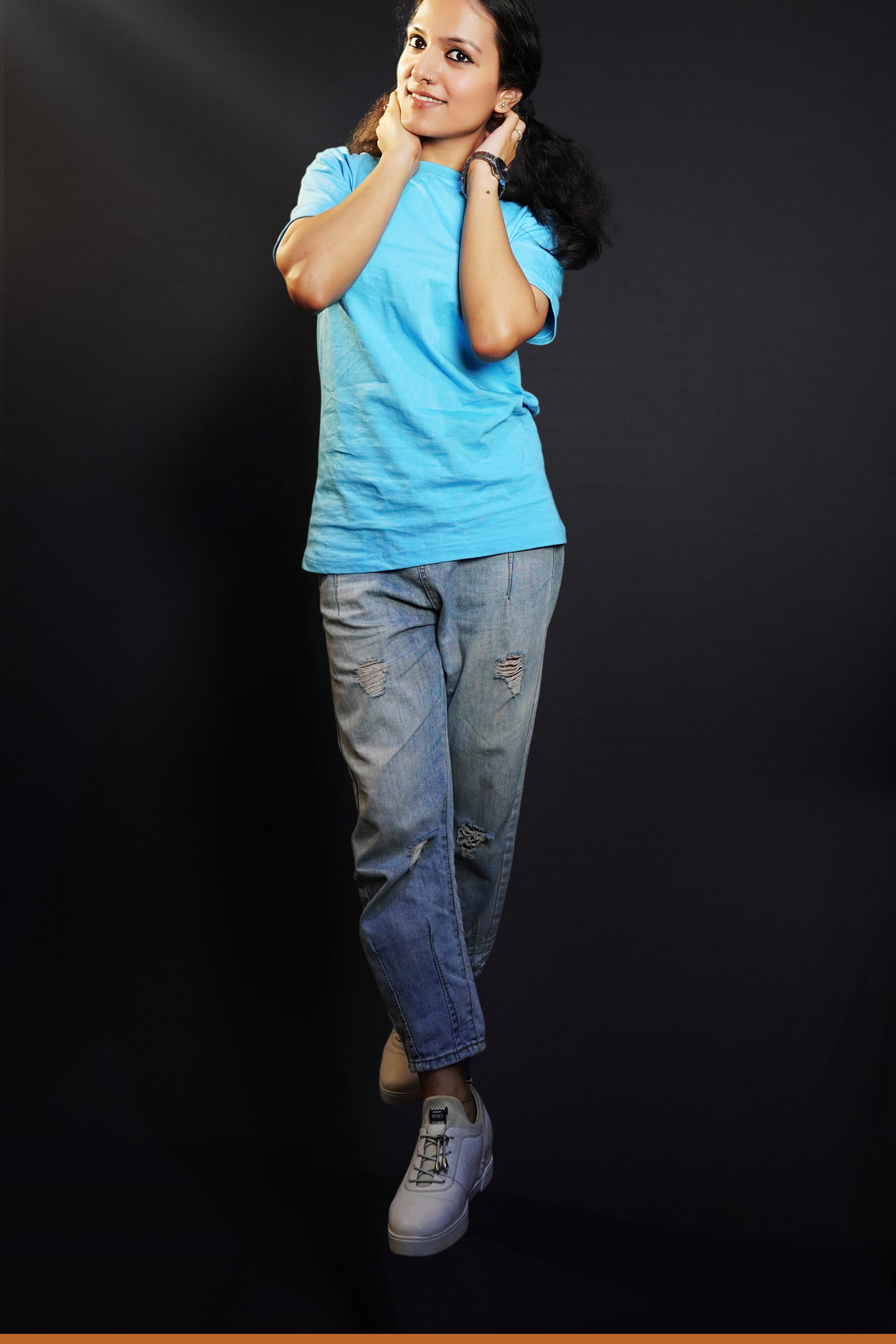 A model wearing cotton plain cloudless blue t-shirt, posing with her hands on the back of her neck, showcasing a cozy in vogue style-Muselot