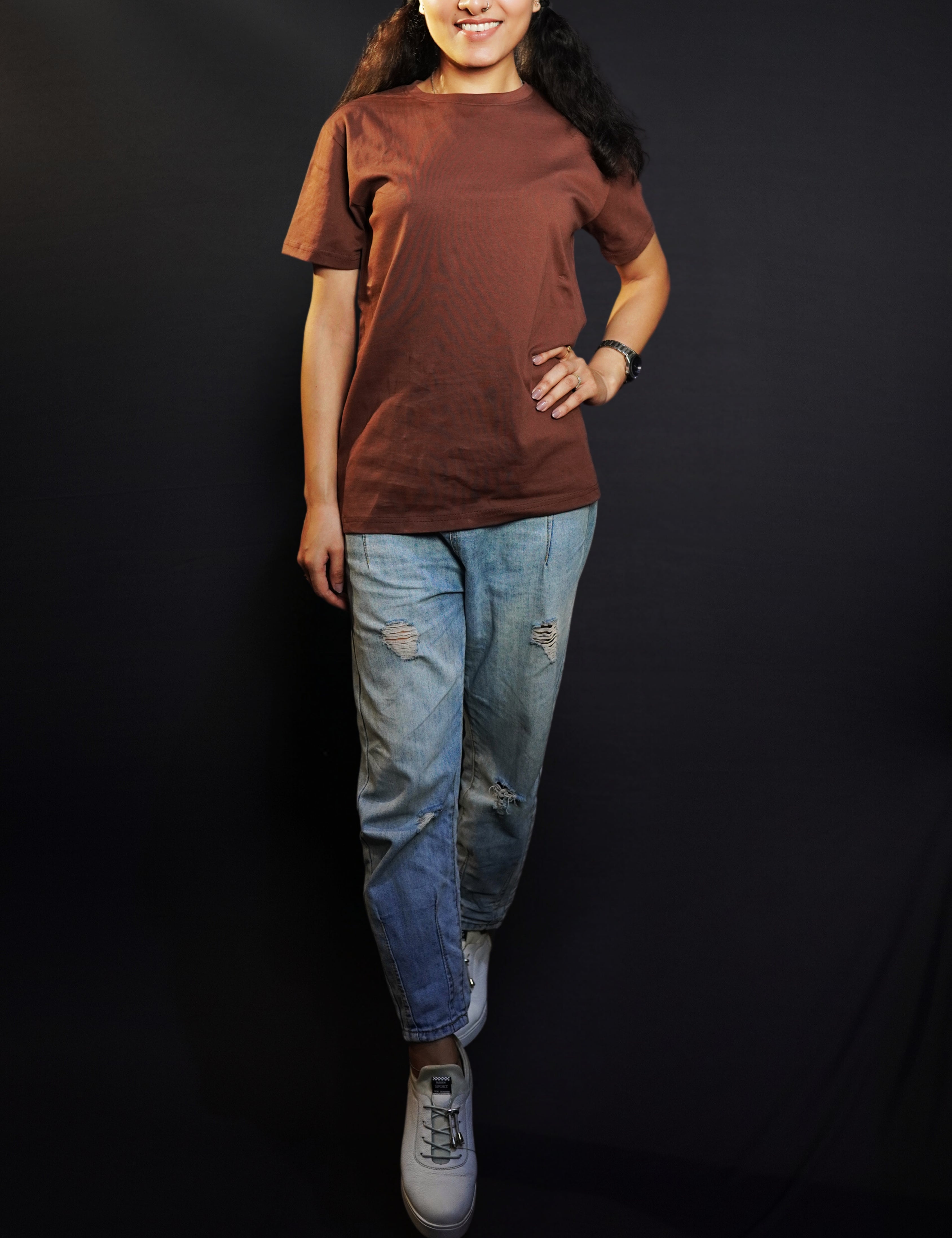 A woman posing happily with her one hand on her waist and other on her side, wearing a round neck plain long length t-shirt, highlighting a soft flexible style-Muselot