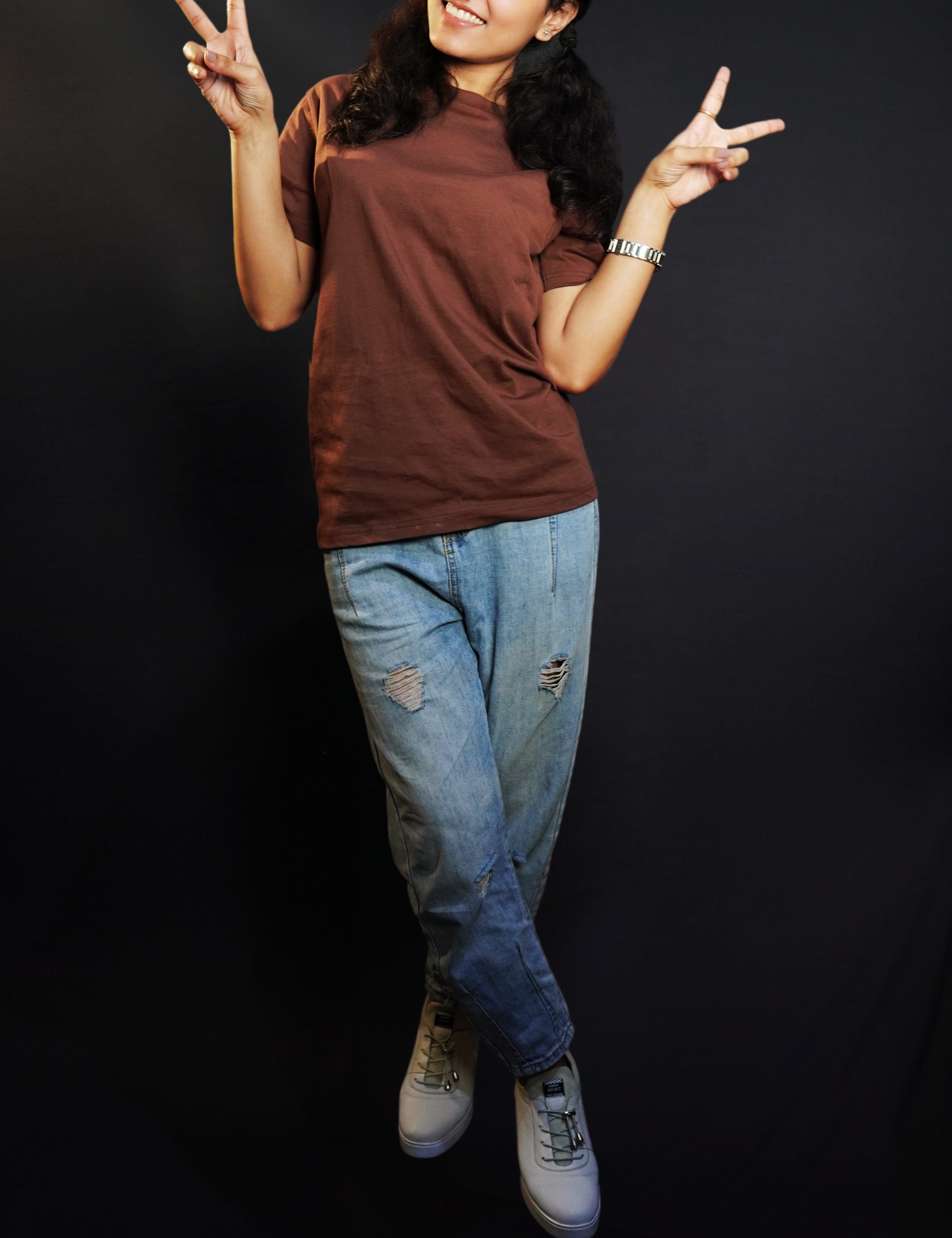 A woman happily posing by making a v sign with her fingers, wearing a plain adults round neck coffee brown t-shirt, showcasing a relaxed snug fit-Muselot