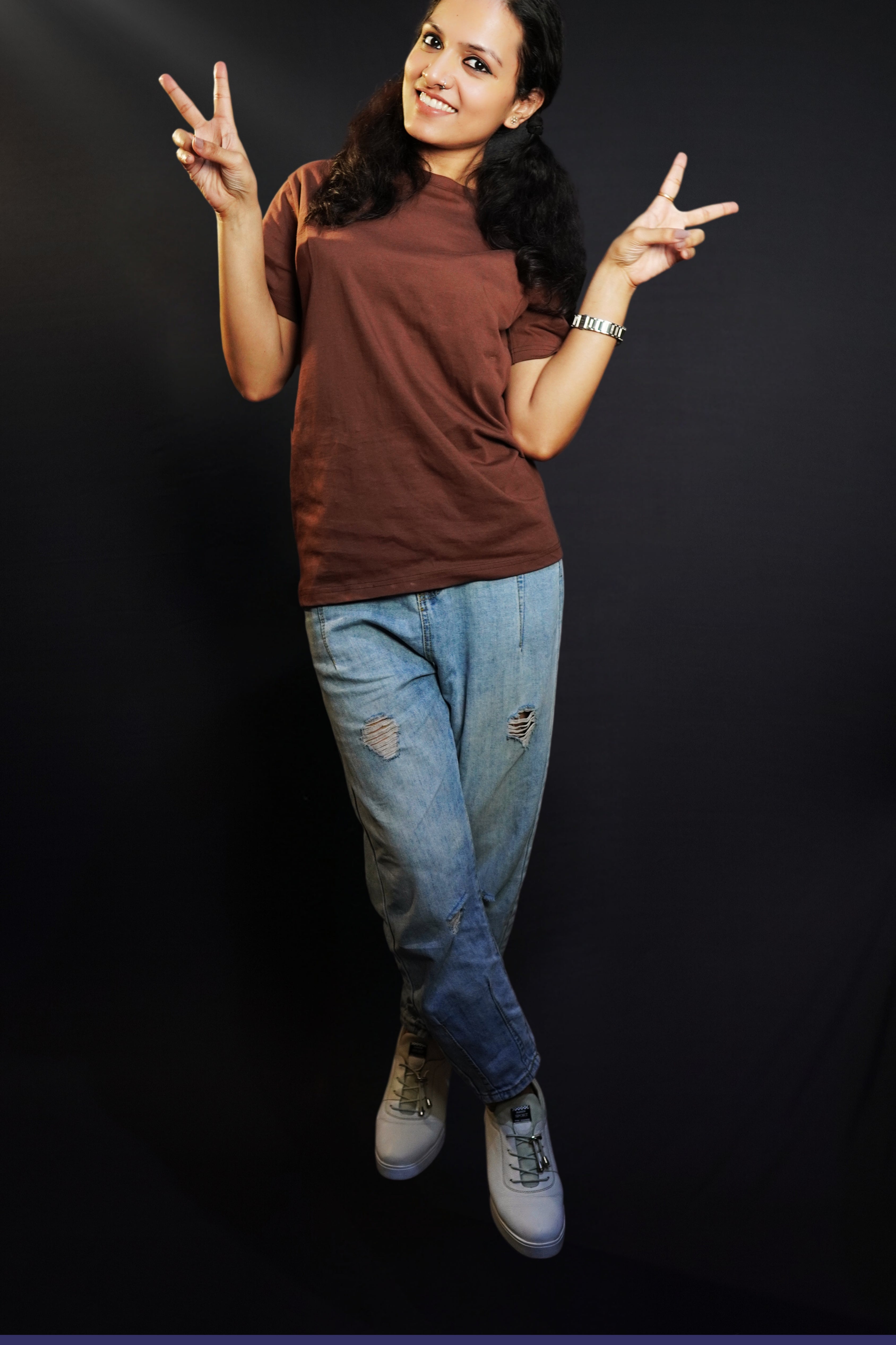 A woman happily posing by making a v sign with her fingers, wearing a plain adults round neck coffee brown t-shirt, showcasing a relaxed snug fit-Muselot