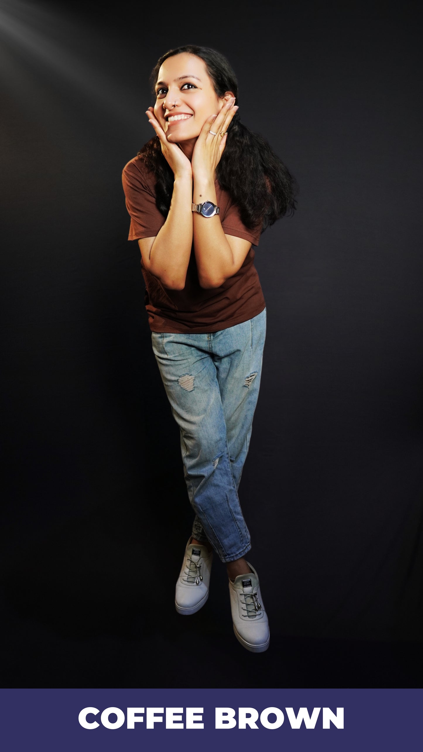 A woman posing happily as her hands caress her face softly, wearing a unisex plain summer coffee brown t-shirt, highlighting a trendy everyday style-Muselot