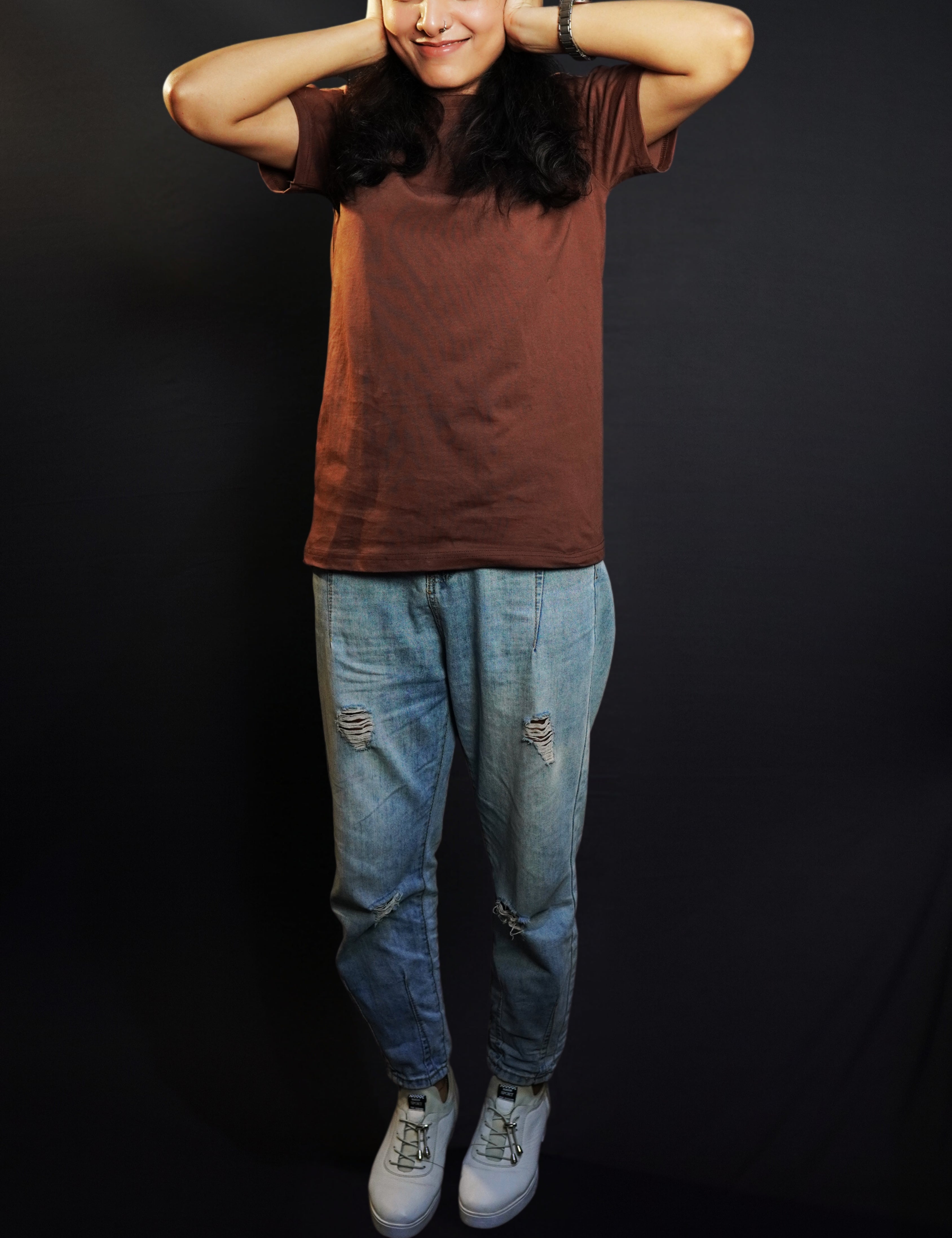 A woman wearing a coffee brown plain stretchable short sleeved t-shirt, posing with her hands on her ears, showcasing a roomy comfortable fit-Muselot