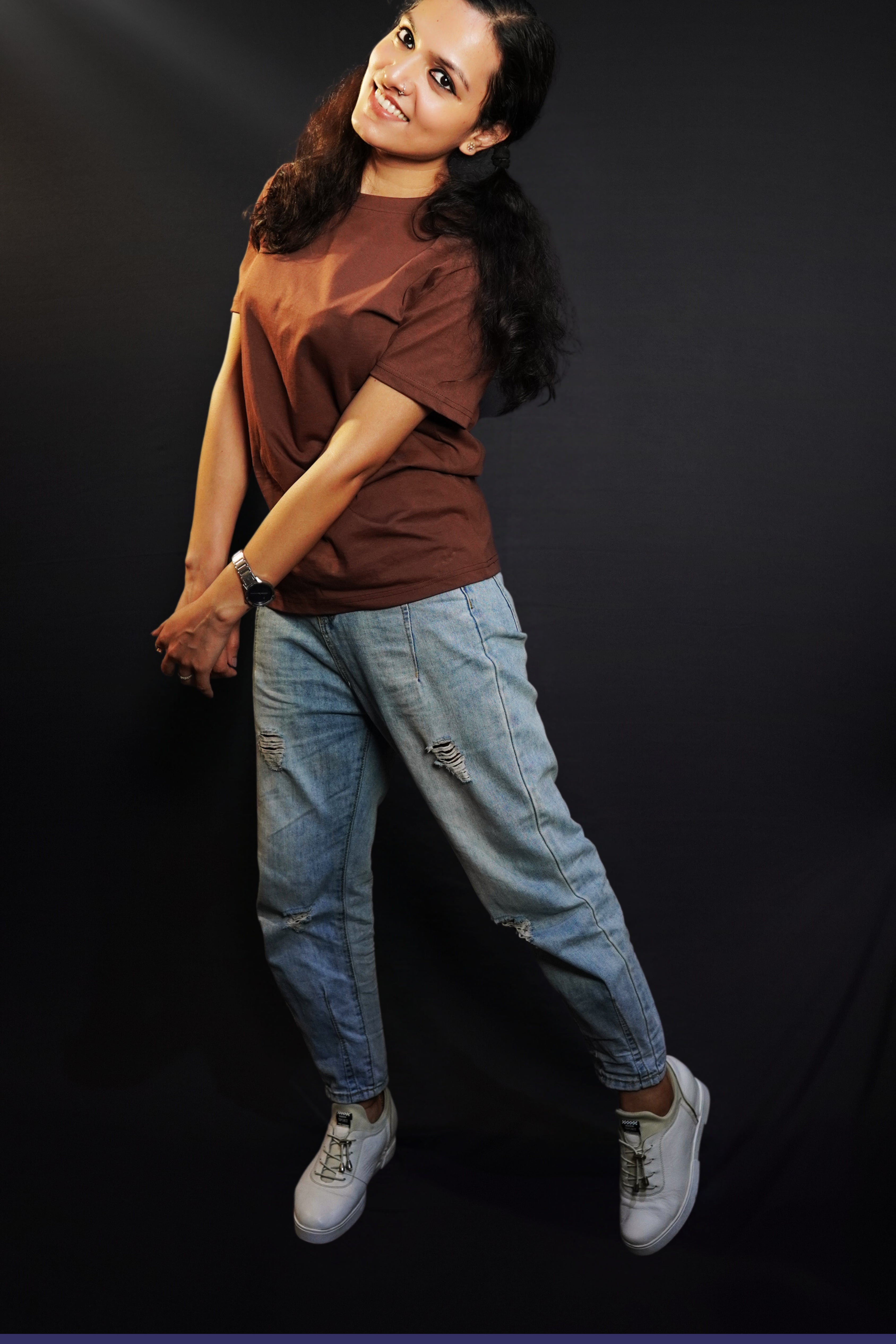A woman posing happily as she sways sideways with her head bent backward, wearing a unisex stretchable round neck coffee brown t-shirt, showcasing a perfect fit style-Muselot