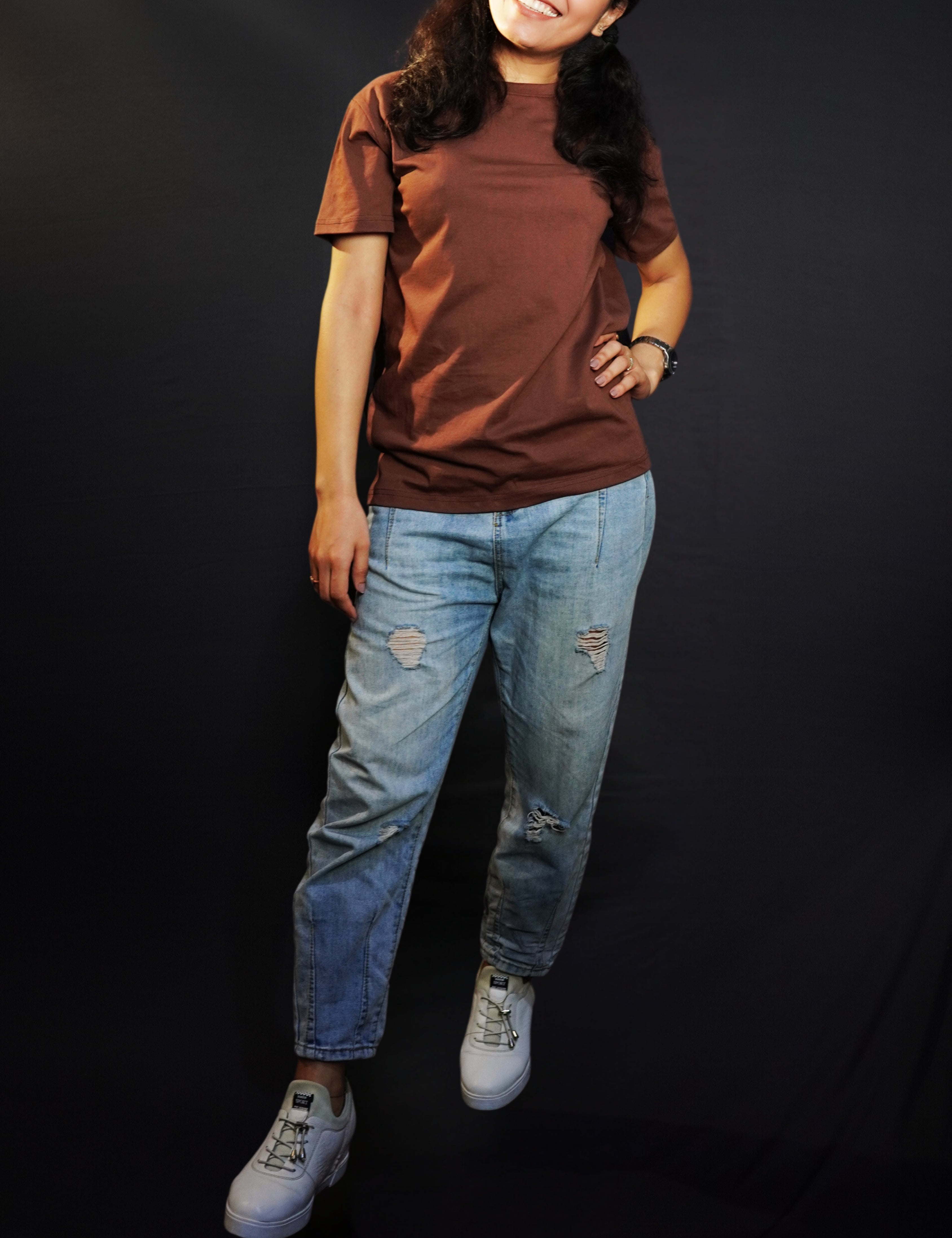 A stylish model posing with a smile and her hand on her waist, wearing a round neck short sleeved women's t-shirt, highlighting a easygoing fit-Muselot