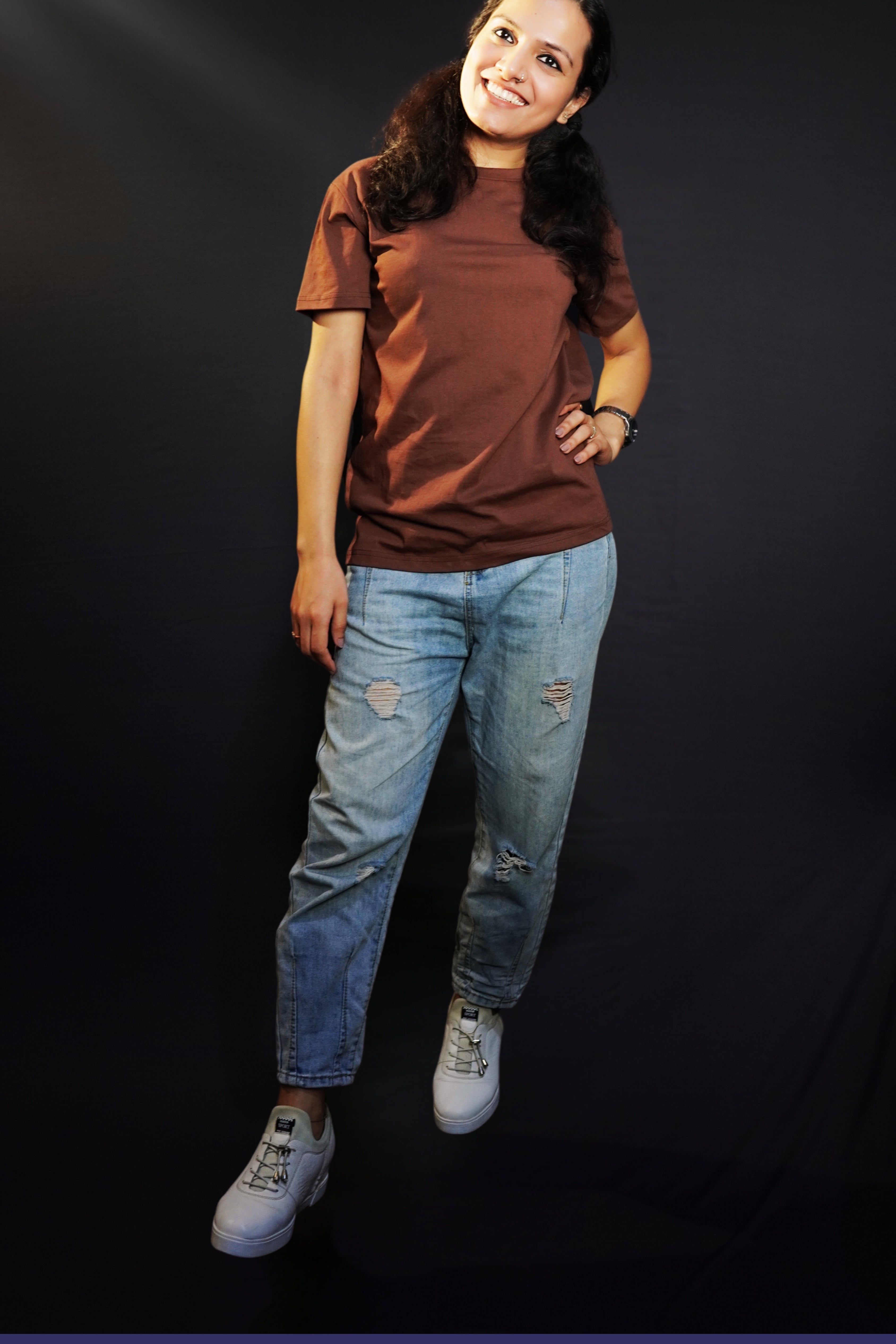 A stylish model posing with a smile and her hand on her waist, wearing a round neck short sleeved women's t-shirt, highlighting a easygoing fit-Muselot