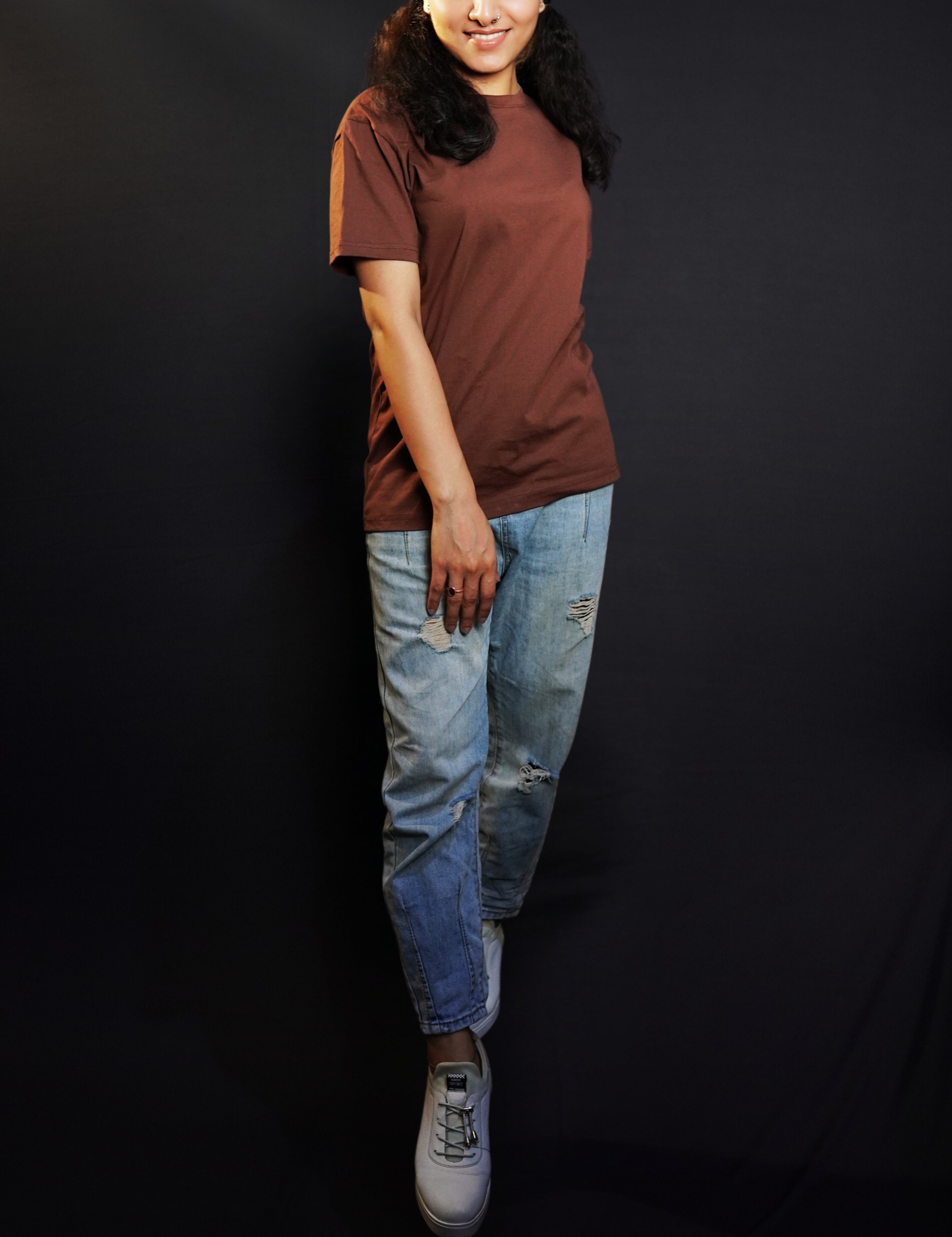 An elegant model posing with her one hand on top of her thigh and other behind her, wearing a cotton unisex plus size summer coffee brown t-shirt, showcasing a modish laid back fit-Muselot