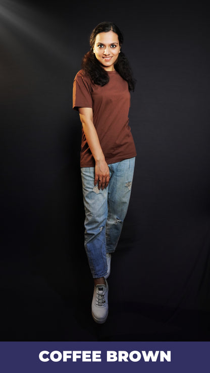 An elegant model posing with her one hand on top of her thigh and other behind her, wearing a cotton unisex plus size summer coffee brown t-shirt, showcasing a modish laid back fit-Muselot