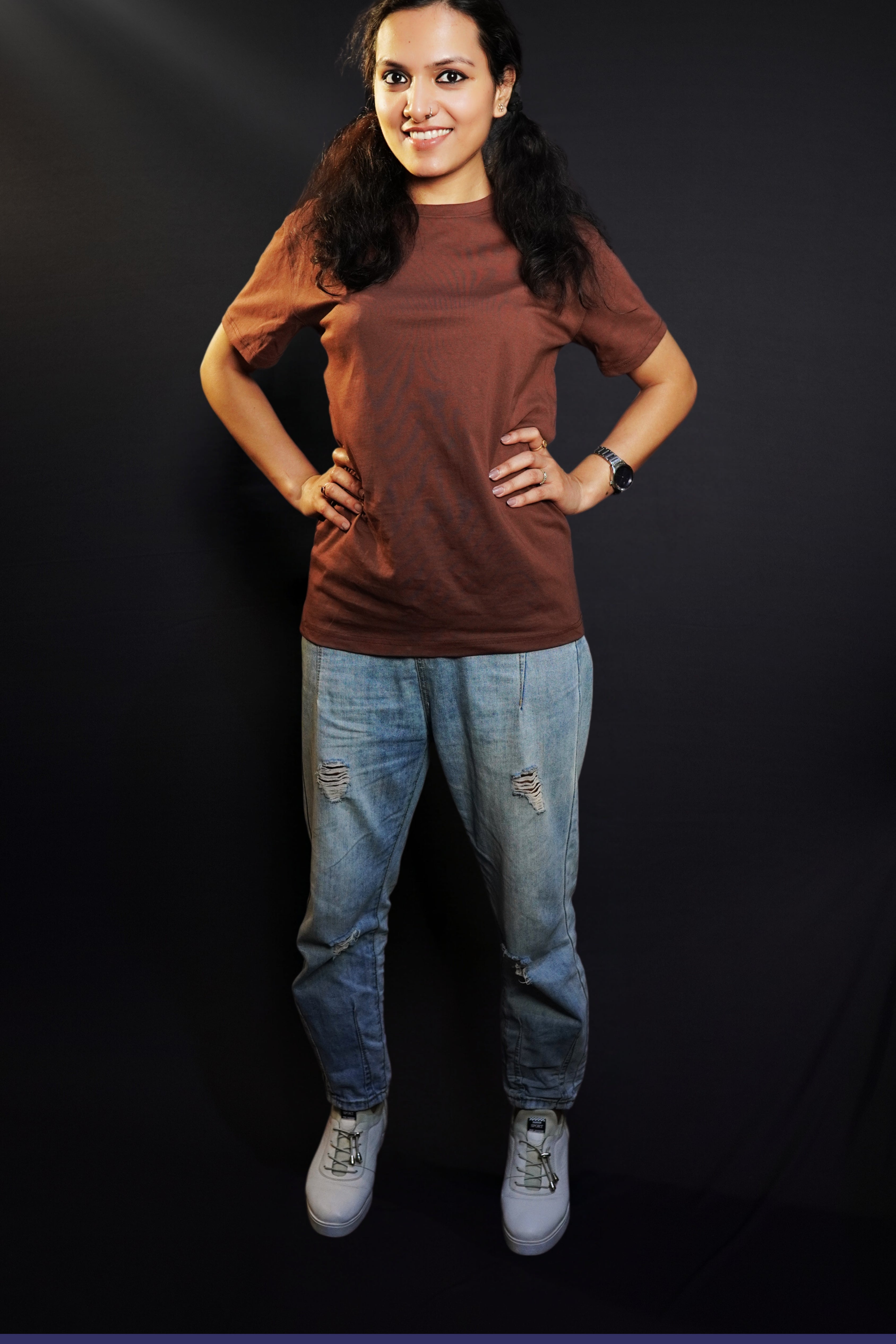 A woman wearing a long plain round neck coffee brown t-shirt, posing with her hands on the sides of her waist, showcasing a flowing voguish style-Muselot