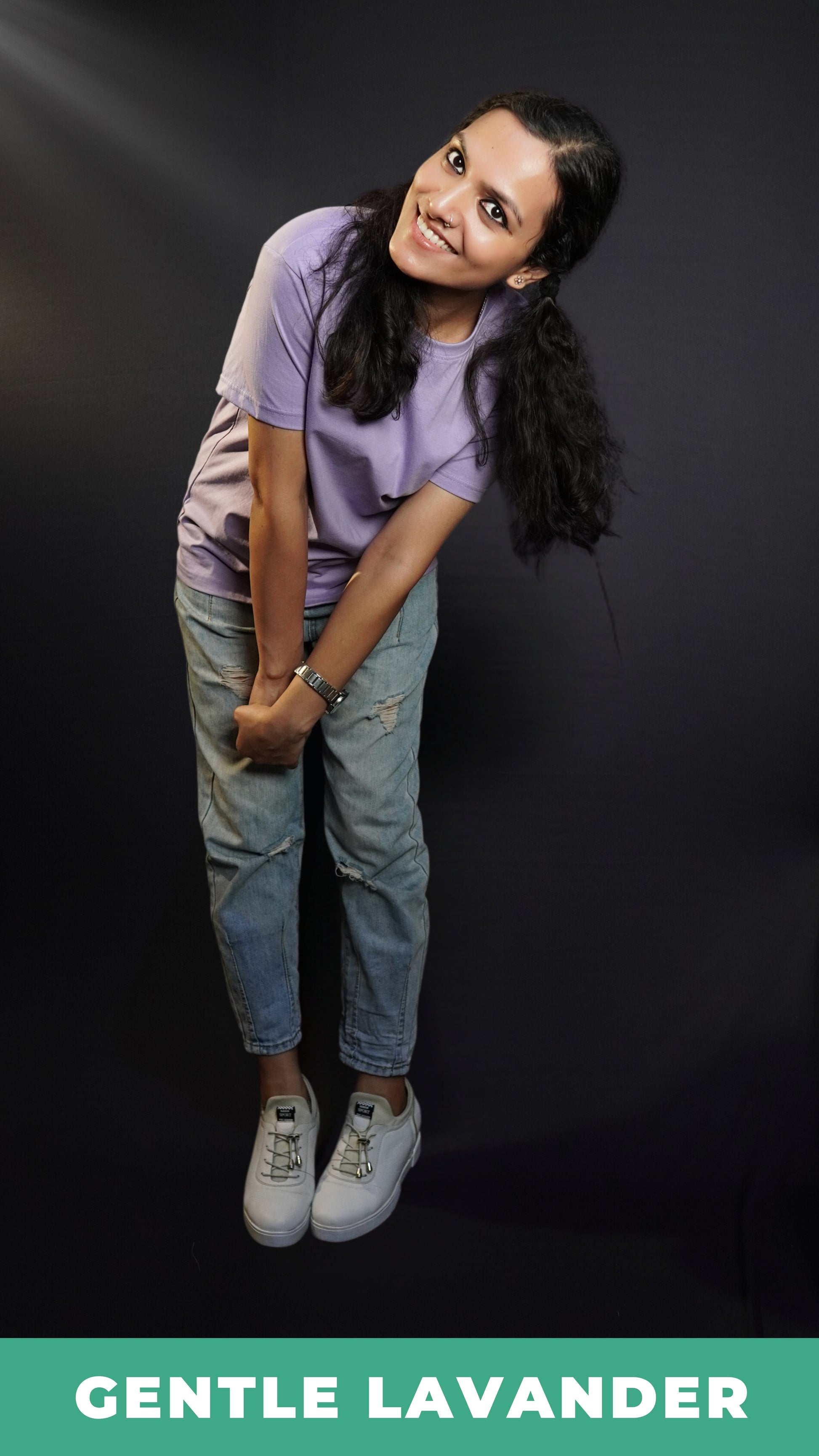 A woman smiling brightly wearing a short sleeved long length women's t-shirt, posing as she bends forward with her hands grabbing each other, highlighting a funky cool style-Muselot