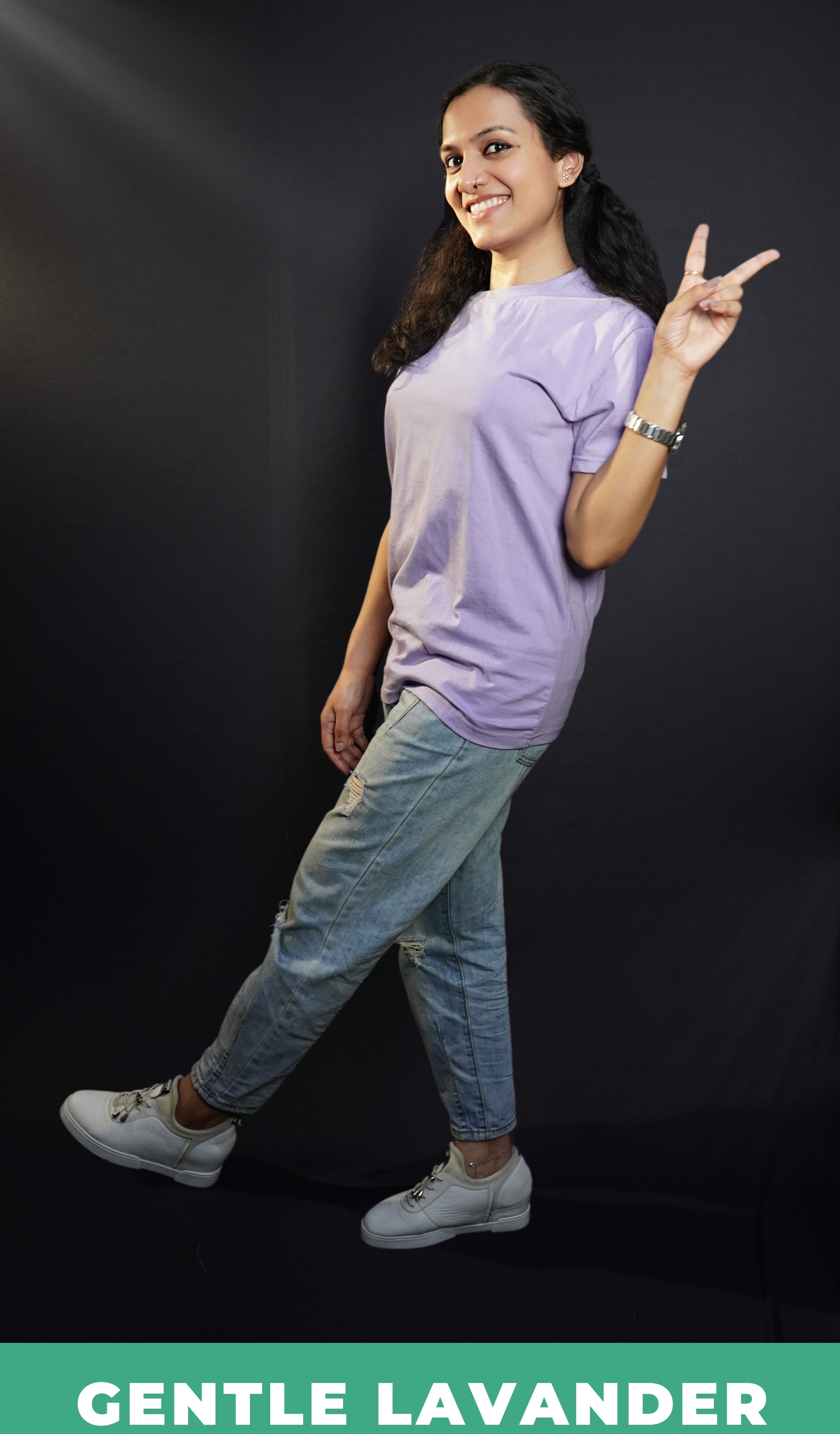 A woman wearing a gentle lavender long length round neck plain t-shirt, posing with her one hand making a v sign, standing sideways, showcasing a cool easygoing fit-Muselot