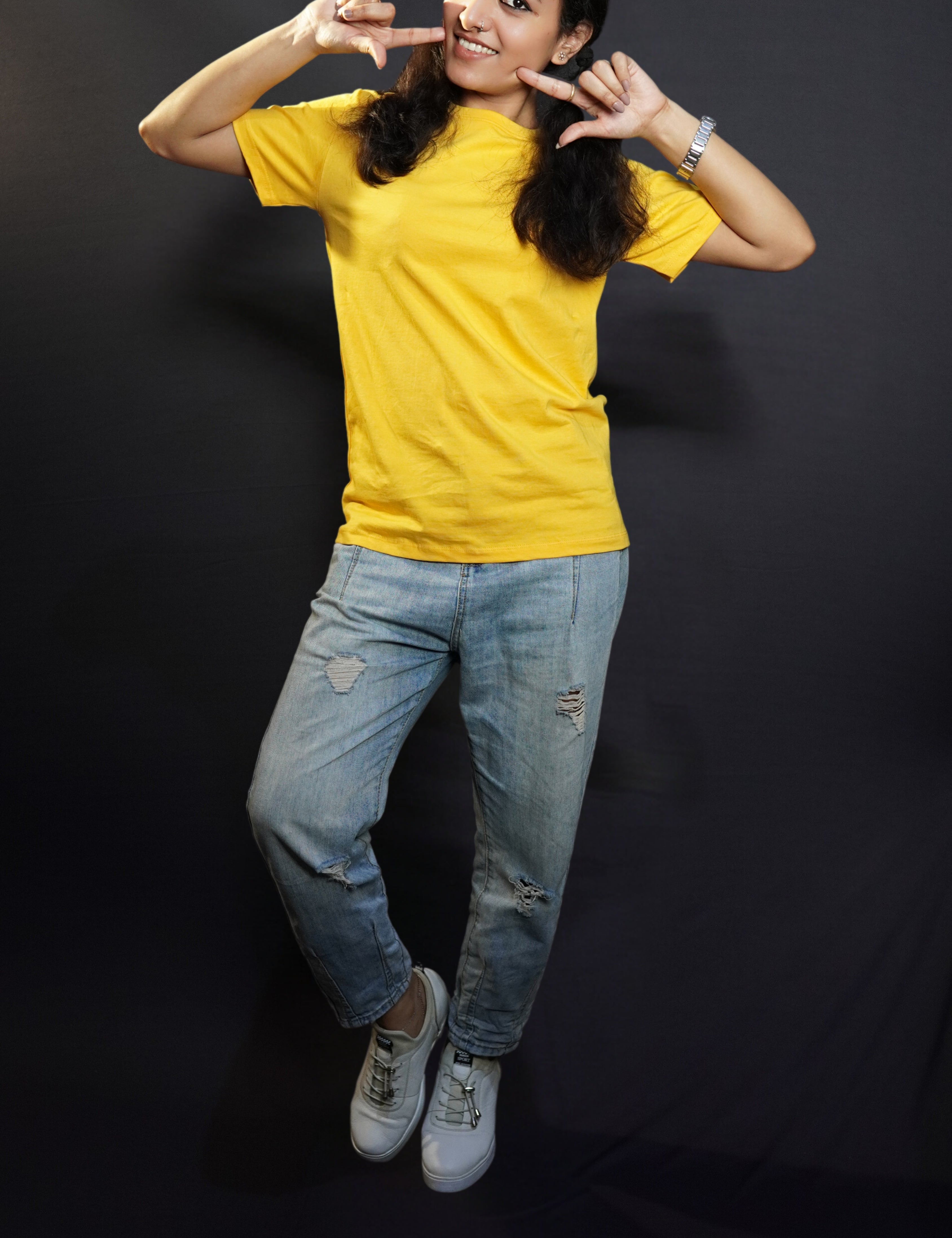A stylish model wearing short sleeved comfortable cotton T shirt paired with blue jeans posing against a dark background-Muselot
