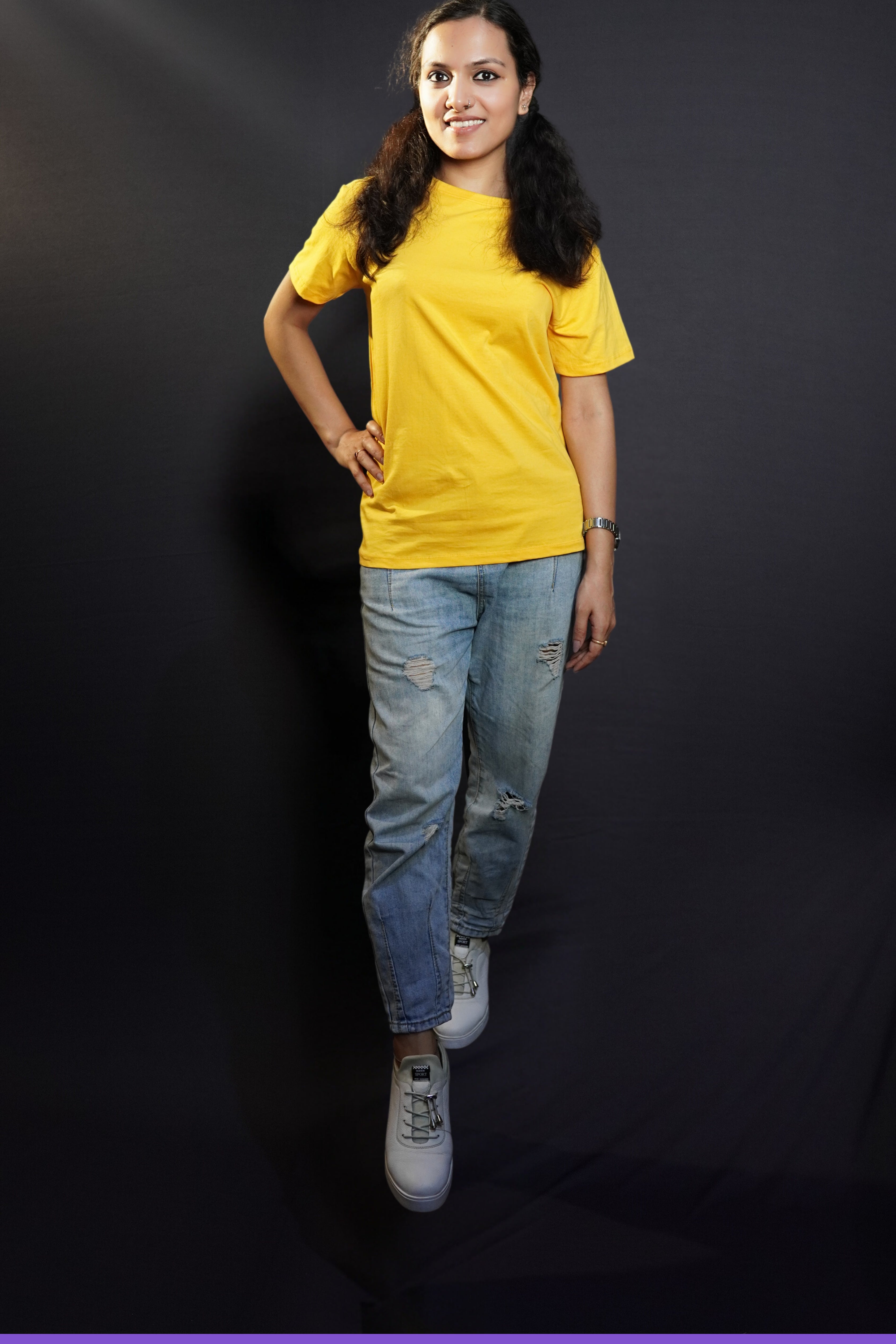 A stylish model wearing plus size stretchable golden yellow T shirt upon ripped jeans smiling brightly at the camera-Muselot