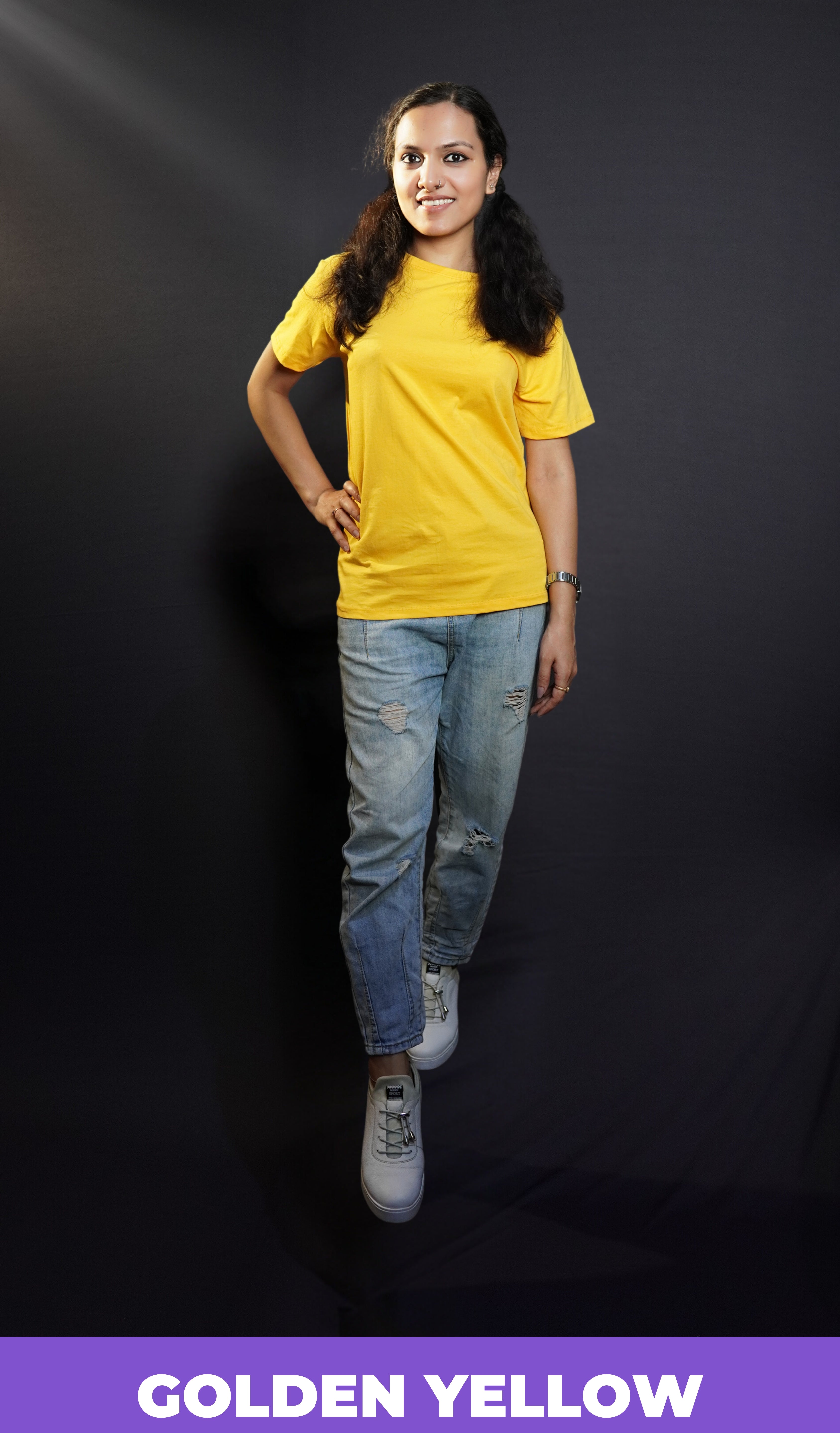 A stylish model wearing plus size stretchable golden yellow T shirt upon ripped jeans smiling brightly at the camera-Muselot